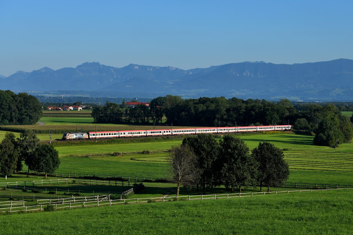 Am Abend des 15. September 2019 eilte 1216.019 mit ihrem EC 84 von Bologna Centrale durch das bayerische Voralpenland bei Aubenhausen ihrem Endpunkt München HBF entgegen. Der klare Spätsommertag sorgte für gute Fernsicht auch die Chiemgauer Alpen samt Kapenwand. 