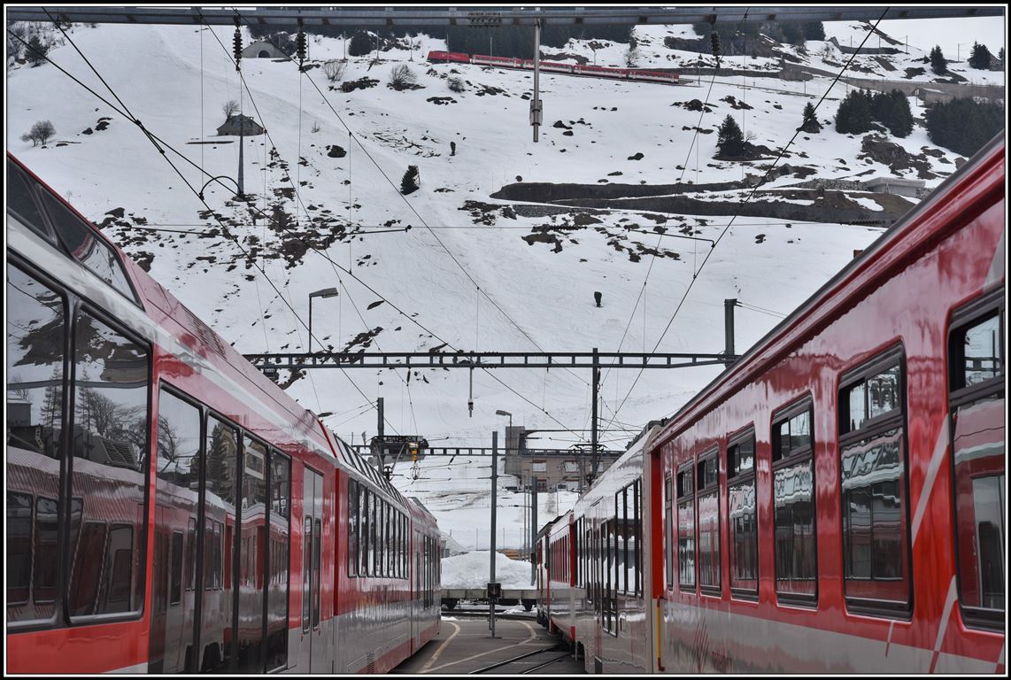 Am Bahnsteig in Andermatt warten R537 nach Visp und R628 nach Göschenen auf die Abfahrt. Am oberen Bildrand fährt R828 mit der HGe 4/4 II 105 Richtung Oberalppass und Disentis. (10.04.2019)