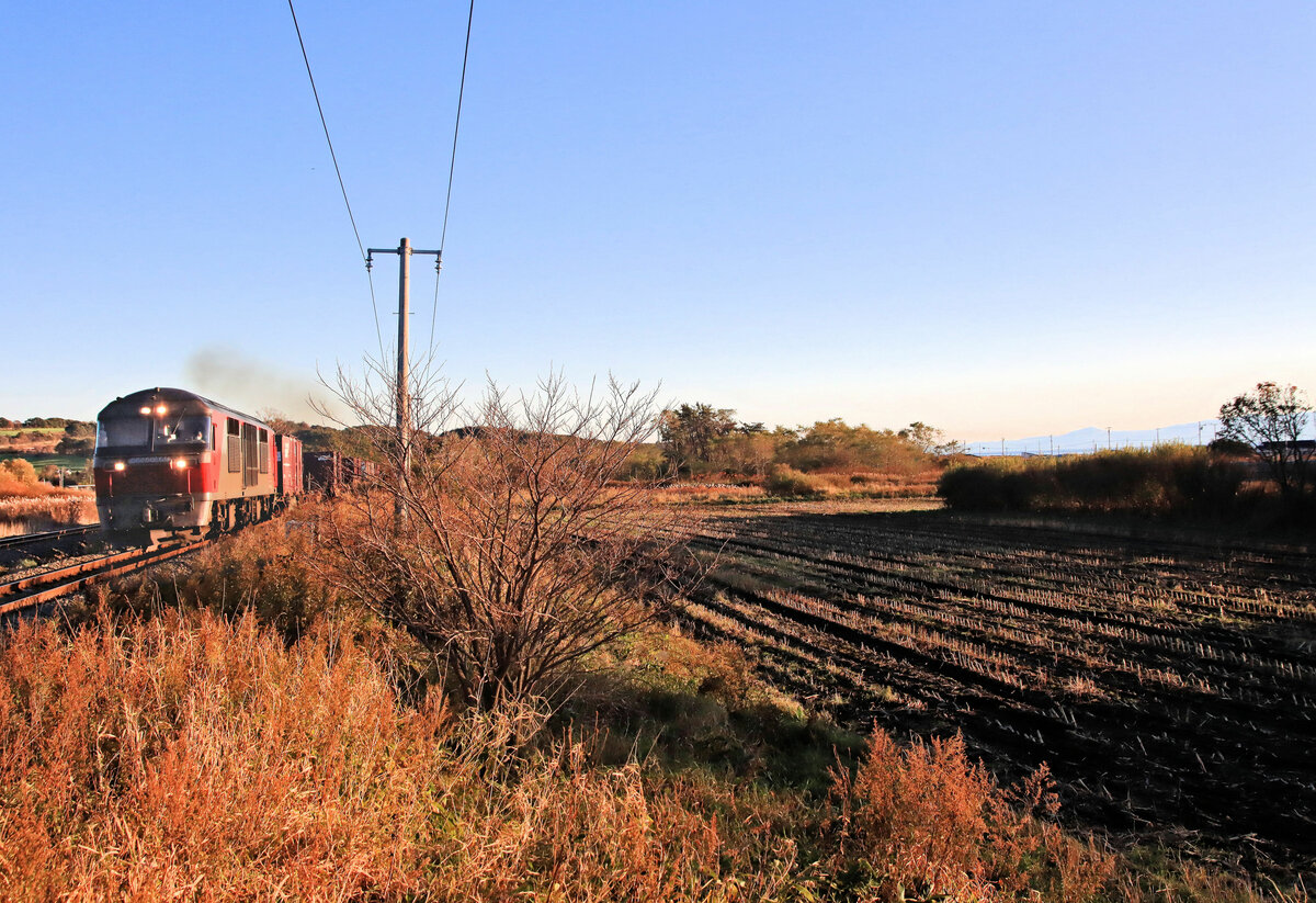 Am Bahnübergang eines kleinen Landwegs in Mareppu (Insel Hokkaidô): Blick aufs Meer, mit einem schweren Güterzug, geführt von der DF200-61. 25.Oktober 2022   
