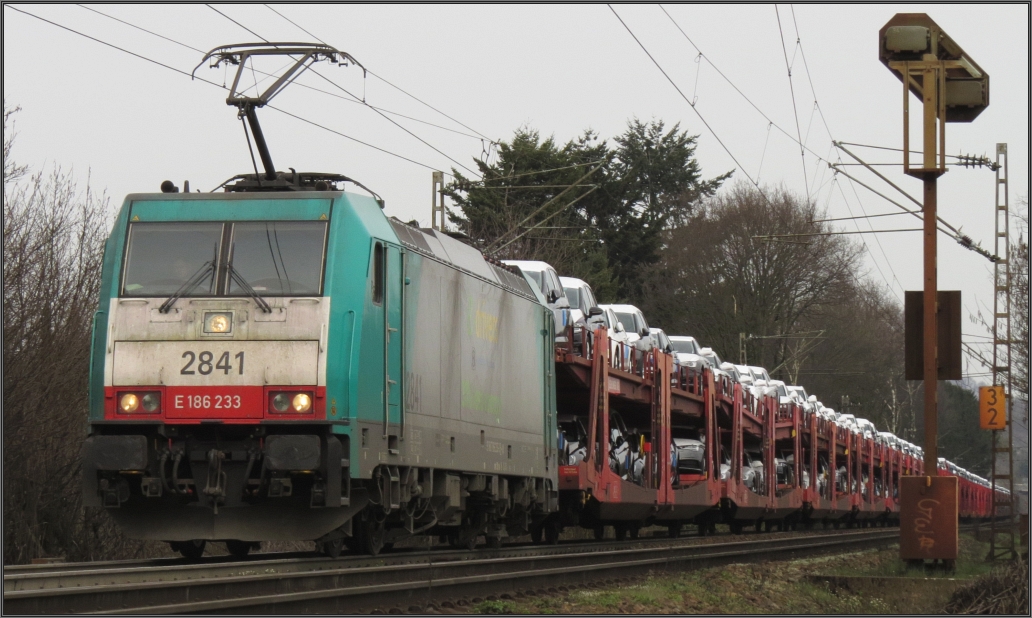 Am frühen Mittag des 02.April 2016 kommt die belgische 2841 abermals die Gemmenicher Rampe hinauf auf der Montzenroute. Diesmal am Haken, ein langer Autotransportzug.
Szenario vom Gemmenicher Weg unweit von Aachen.