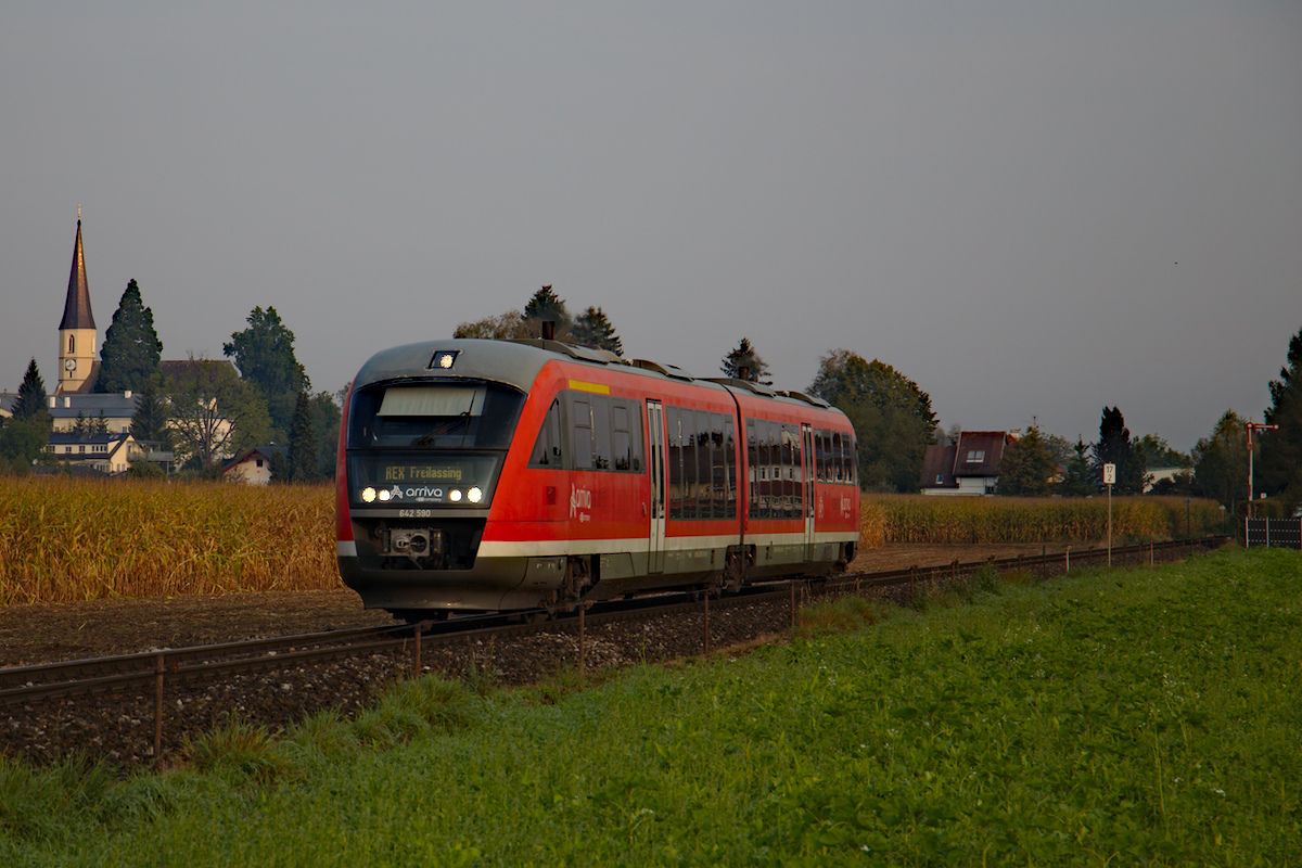 Am frühen Morgen ist der DB 642 590 als REX 5858 von Braunau am Inn nach Freilassing unterwegs. Links vom Triebwagen die Kirche von Mattighofen, rechts das Einfahrsignal in den Bahnhofs. (13.09.2020)