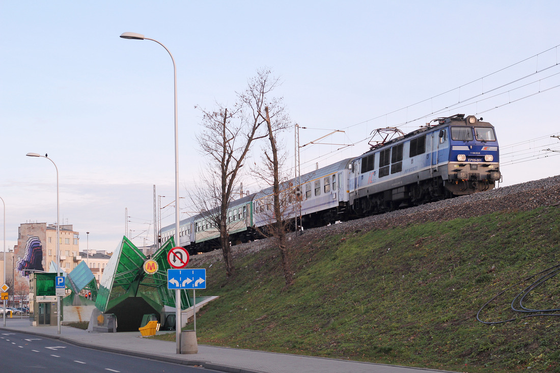 Am frühen Morgen des 7. Dezember 2015 konnte ich EP 09-001 mit einem Fernverkehrszug ablichten.
Das Foto entstand im Bereich der Station Warszawa Stadion.