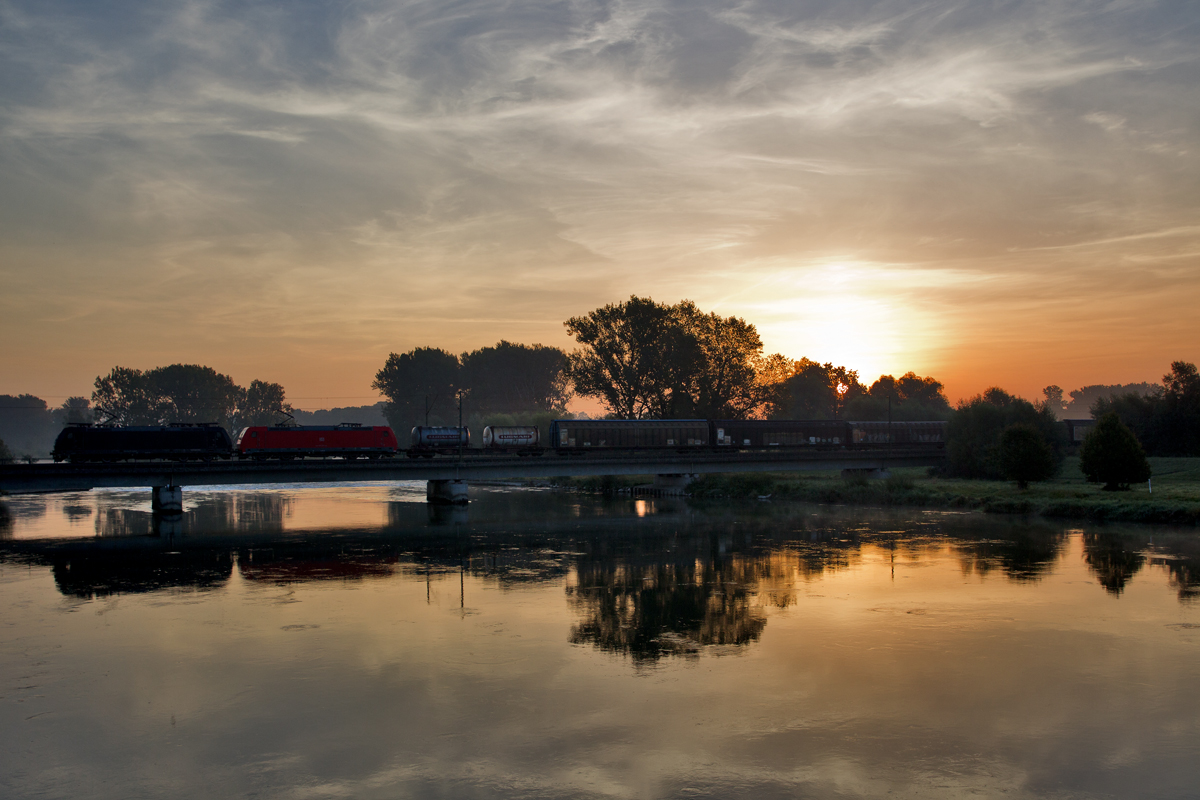 Am frühen Morgen fährt eine Doppeltraktion zweier unbekannt gebliebener Eloks der BR 185 mit einem gemischten Güterzug über die Isarbrücke in Plattling.Bild vom 12.9.2016