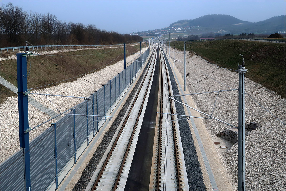 Am Fuße der Schwäbischen Alb - 

Eindrücke von der Schnellfahrstrecke Wendlingen - Ulm. 

Hier geht der Blick in Richtung Ulm von der Brücke über die Bahnstrecke bei Holzmaden. Im Hintergrund der Aichelberg und der Turmberg. An der hellen Raute unten am Berg links oberhalb des rechten Oberleitungsmasten befindet sich das Portal des Boßlertunnels im Bereich des Albaufstiegs. Etwas steiler als die Bahn erklimmt auch die Autobahn A8 die Schwäbische Alb. Deren Verlauf kann an einzelnen LKWs am Berg erkannt werden.

18.03.2022 (M)