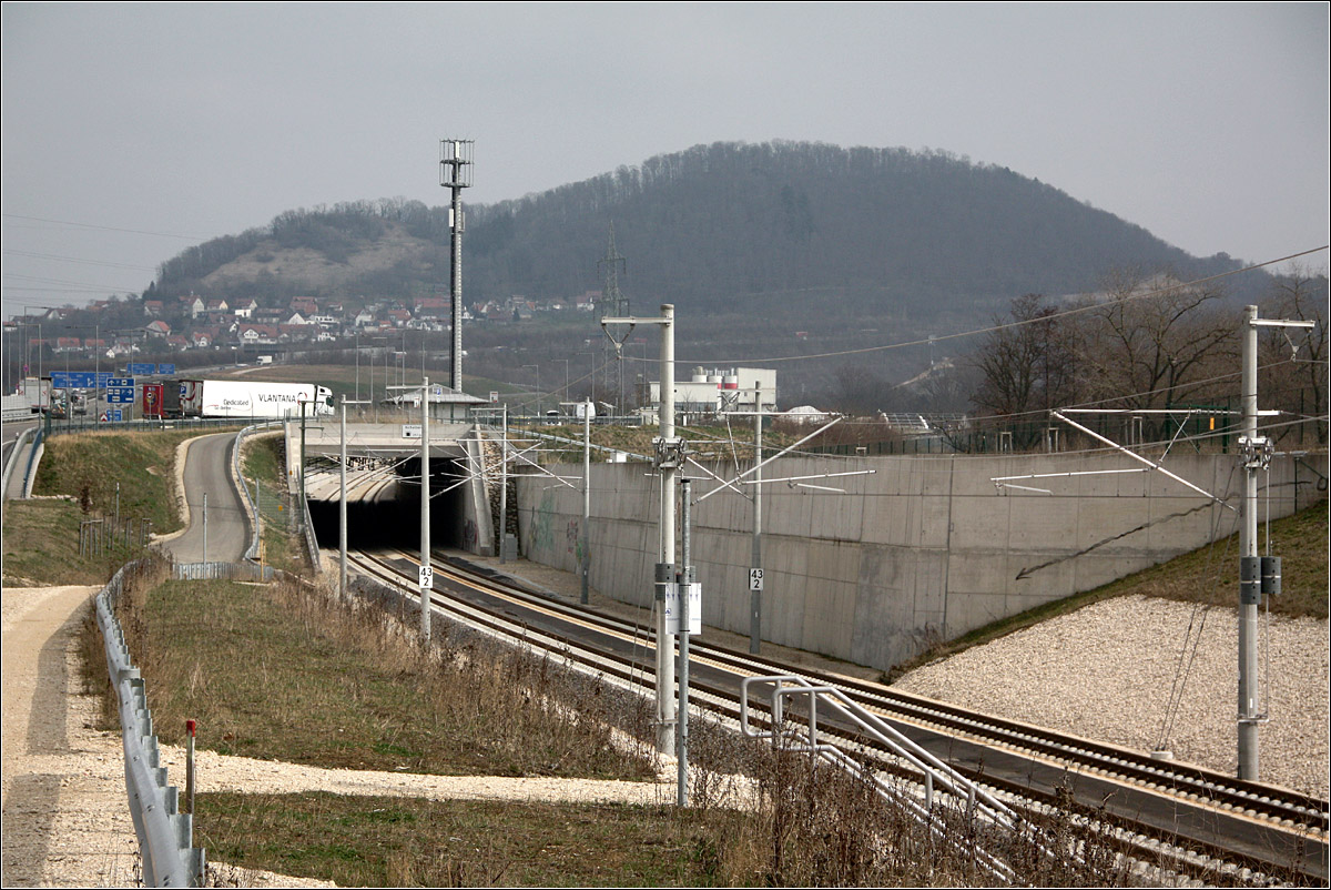 Am Fuße der Schwäbischen Alb - 

Eindrücke von der Schnellfahrstrecke Wendlingen - Ulm. 

In der Senke der Strecke innerhalb des Tunnels unter der Rastanlage 'Vor dem Aichelberg' beginnt der Albaufstieg der Schnellfahrstrecke und zwar gleich mit einer maximalen Steigung von 31 ‰ etwa bis zur Autobahnanschlusstelle Aichelberg. Dann geht es mit ca. 24 ‰ weiter durch den Boßlertunnel, die Steigung auf der Filstalbrücke beträgt etwa 23 ‰, im folgenden Steinbühltunnel beträgt die Steigung 17,3 - 25 ‰. Während am Beginn des Albaufsieges die Strecke auf 361 m ü. NN liegt, erreicht sie am Ostportal des Steinbühltunnels 746 m ü. NN. 

Hinweis: Der Feldweg zwischen Autobahn und Bahnstrecke ist offen zugänglich, was ich nicht erwartet hatte.

18.03.2022 (M)