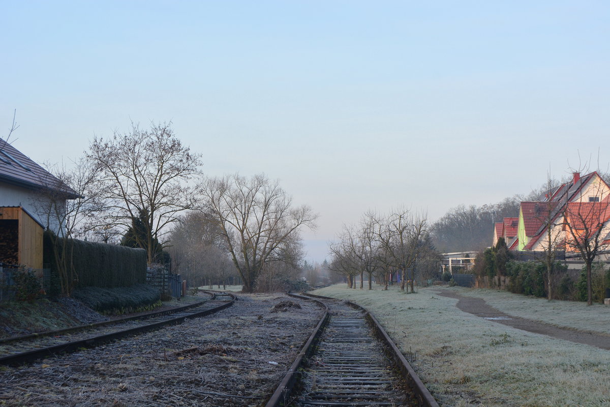 AM Gleisverlauf erkennt man gut das hier einst mehr Gleise lagen. Links zweigte die ehemalige Vaihinger Stadtbahn ab welche bis 2002 vom T04 der WEG befahren wurde. Rechts ist eines der ehemaligen Gleise der Westbahn welche 1991 im Zuge der Neubaustrecke umtrassiert wurde. Bis 2003 war dies noch ein Anschlussgleis. Seit der Umtrassierung 1991 verkehrte auf der ehemaligen Westahn nur noch regionaler Güterverkehr und der Triebwagen T04 der WEG nach Enzvaihingen. 2002 wurde der Personenverkehr eingestellt und die Strecke ab Vaihingen Enz Nord bis Enzvaihingen 2003 wegen Oberbaumängeln gesperrt. Bis August 2003 verkehrte Cargo noch mit Übergaben von Sersheim bis Vaihingen Enz Nord. Nun werden Teile der Strecke abgebaut und zum Radweg umgebaut. 

Vaihingen 28.12.2019