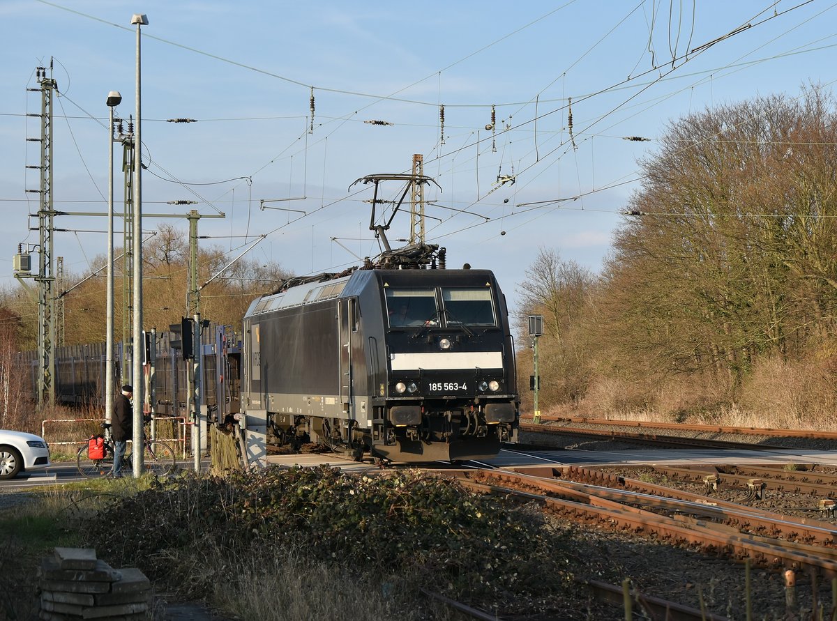 Am heutigen Nachmittag kommt die MRCE 185 563-4 bringt für die Ford-Werke einen leere Autotransportwagenzug über die Kbs 465, die Lok ist hier auf dem BÜ Blumenstraße. 24.3.2018
