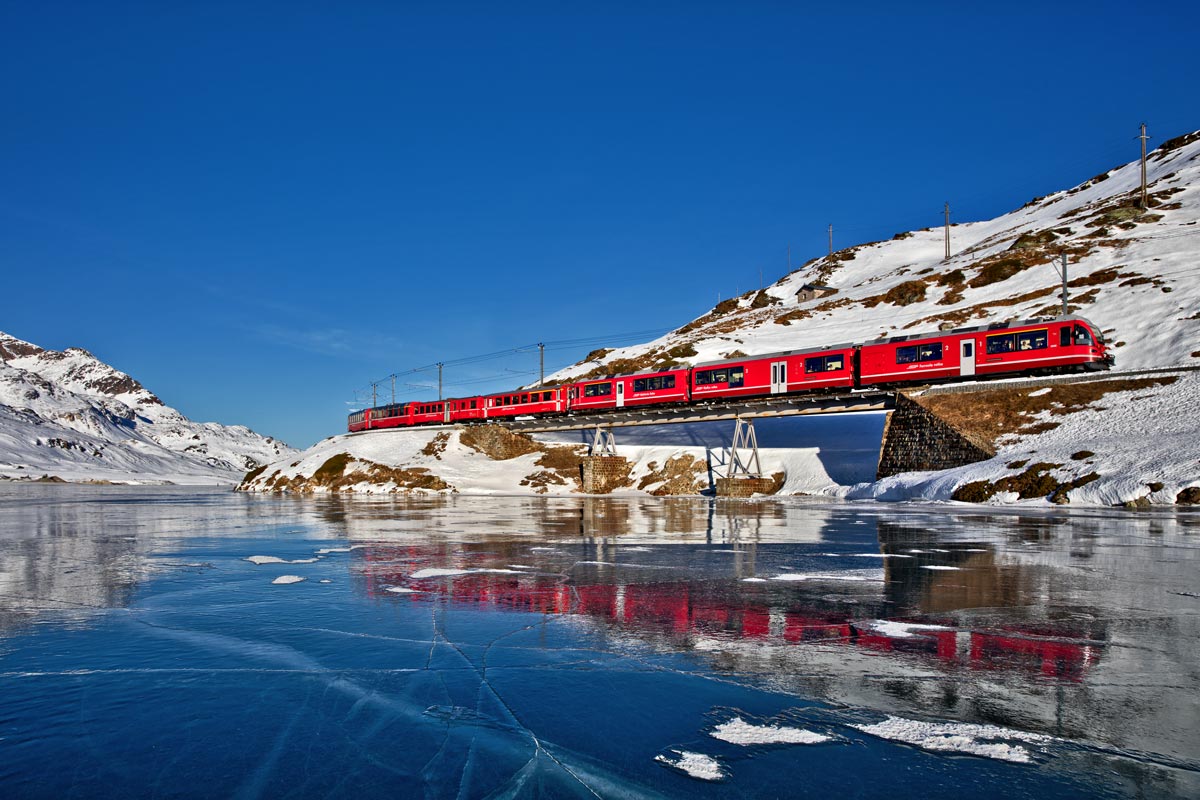 Am mit Schwarzeis bedeckten Lago Bianco fährt der RhB Triebzug ABe 8/12 3508 mit einem BEX Richtung Süden.Bild vom 28.12.2016