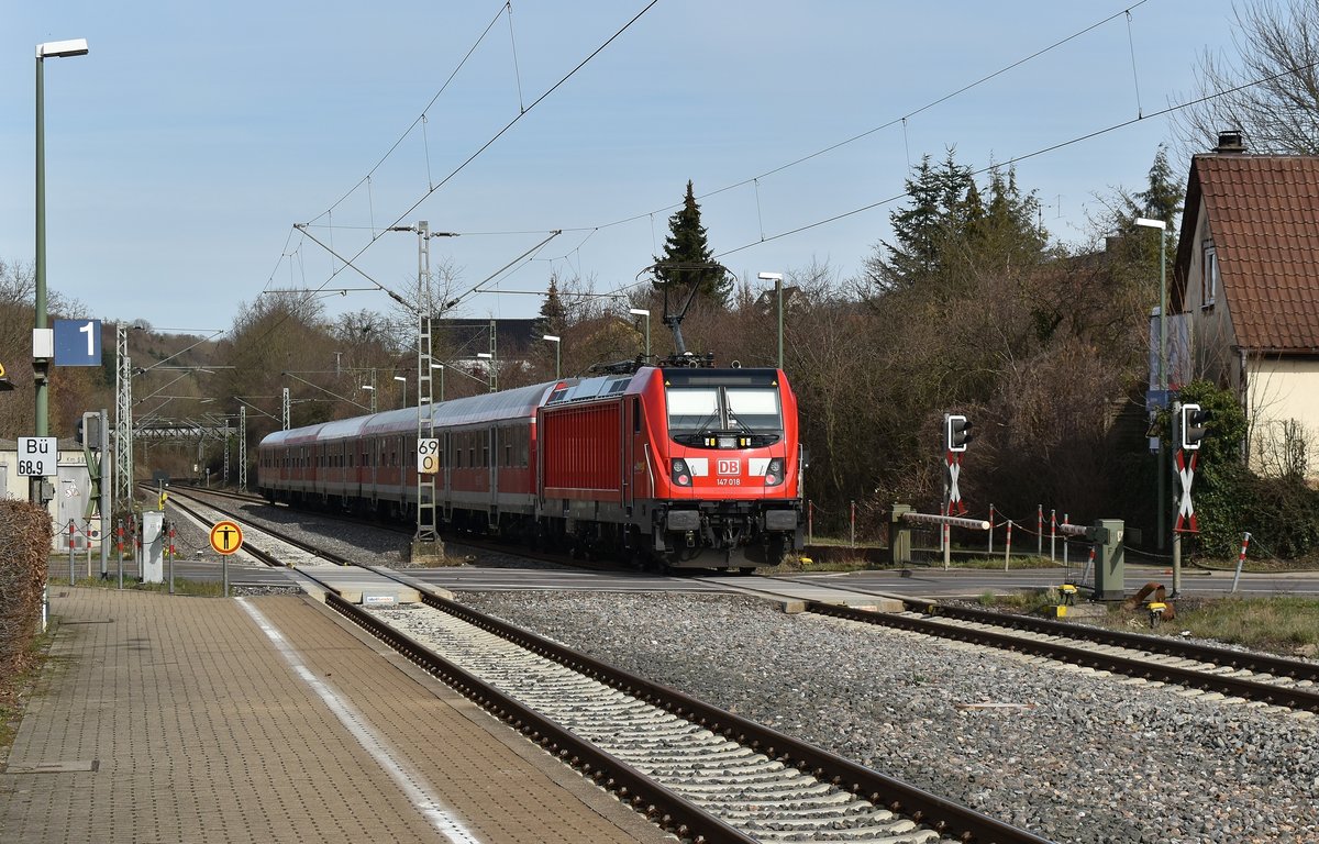 Am Mittag des 6.März 2019 ist die 147 018 als RB19114 nach Lauda unterwegs, ab wo die Strecke wegen Tunnelarbeiten gesperrt ist. Das Bild zeigt den Zug in Untergriesheim am Bahnsteig Gleis 2. Die Maschine stellt hier noch den Bü zu, so das die Schranke geschlossen bleiben muss und der Straßenverkehr warten muss. 