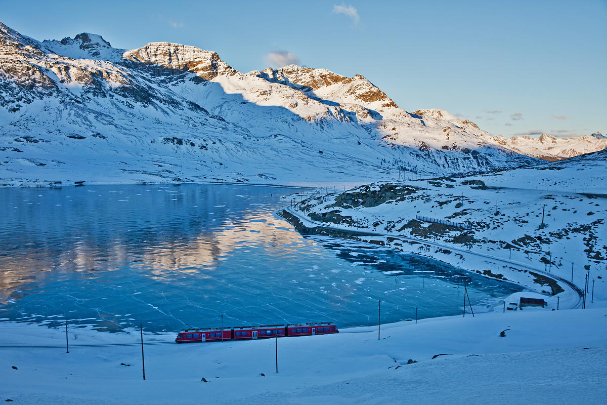 Am Morgen de 28.12.2016 fährt der RhB Triebzug ABe 8/12 3512 am schwarzgefrorenen Lago Bianco entlang.