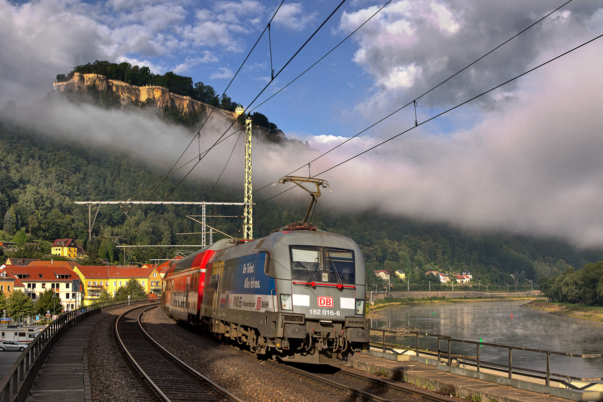 Am Morgen des 7.9.2015 verzieht sich langsam der Nebel im Elbtal und gibt die Sicht frei auf die Festung Königstein,in diesem schönen Moment fährt die S1 Meissen-Triebischtal bespannt mit der 182 016-6 in Königstein vorüber.
Und noch viele Grüsse an den Bahnwächter ;O