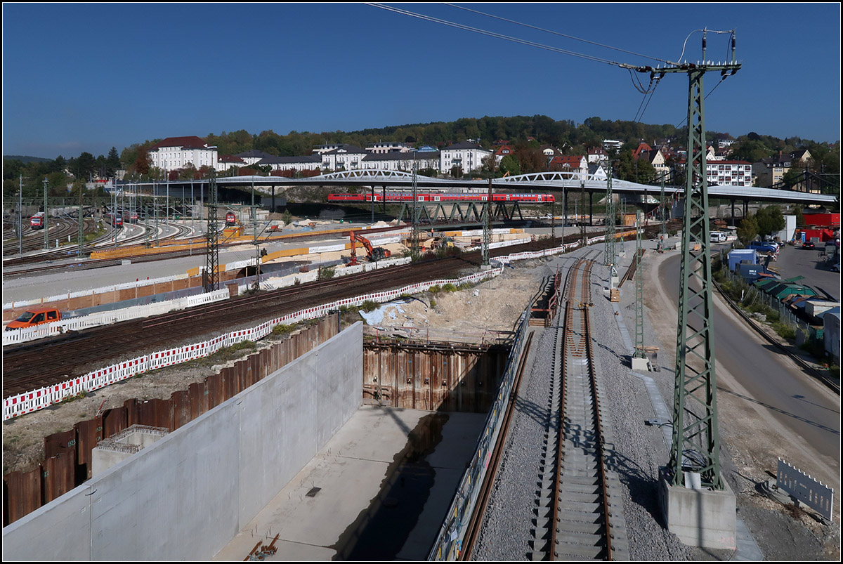 Am Nordkopf des Ulmer Hauptbahnhofes -

... endet die Neubaustrecke aus Stuttgart. Von der Autobahn A8 auf der Schwäbischen Alb kommend führen die Gleise im 5,9 Kilometer langen Albabstiegstunnel hinunter nach Ulm und kommen im Hintergrund unterhalb des Dosto-Zuges ans Tagelicht, unterqueren die Stecke aus Aalen unter der neuen Fachwerkbrücke sowie die Strecke aus Geislingen in einem noch zu bauenden kurzen Tunnel um dann nach einem Rampenbauwerk (vorne unten) in den Ulmer Hauptbahnhof einzufädeln.

In Hochlage über den DB-Gleisen ist die langgezogene, elegant gestaltete Kenlesbergbrücke zu sehen, auf der ab Dezember die neue Ulmer Straßenbahnlinie 2 verkehren soll. Gleichzeitig können auch Radfahrer und Fußgänger die Brücke überqueren.

04.10.2018 (M)