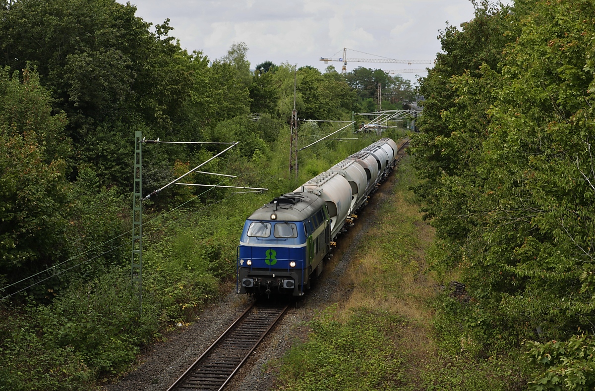 Am Rande der Düsseldorfer Innnenstadt befördert die NIAG 8 am 13.08.2019 den Sodazug von Millingen nach Düsseldorf-Reisholz (Henkel-Werke) über die Güterumgehungsbahn. Das üppige Grün täuscht, links befinden sich hinter den Bäumen Gewerbebetriebe, rechts der Betriebshof Lierenfeld der Rheinbahn. Bei der NIAG 8 handelt es sich um die ex-DB 216 111, die im Jahre 2000 bei On Rail zur DH1504 umgebaut wurde.