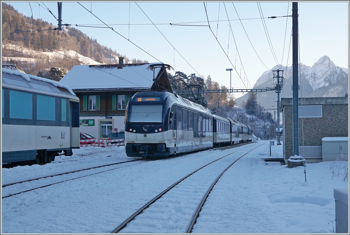 Am Schluss des GoldenPass Panoramic PE 2212 von Montreux nach Zweisimmen läuft der Alpina ABe 4/4 9303 mit. Der Zug ist hier beim Halt in Rossinière zu sehen, links im Bild steht ein MOB Panoramawagen auf einem Abstellgleis.

11. Jan. 2021