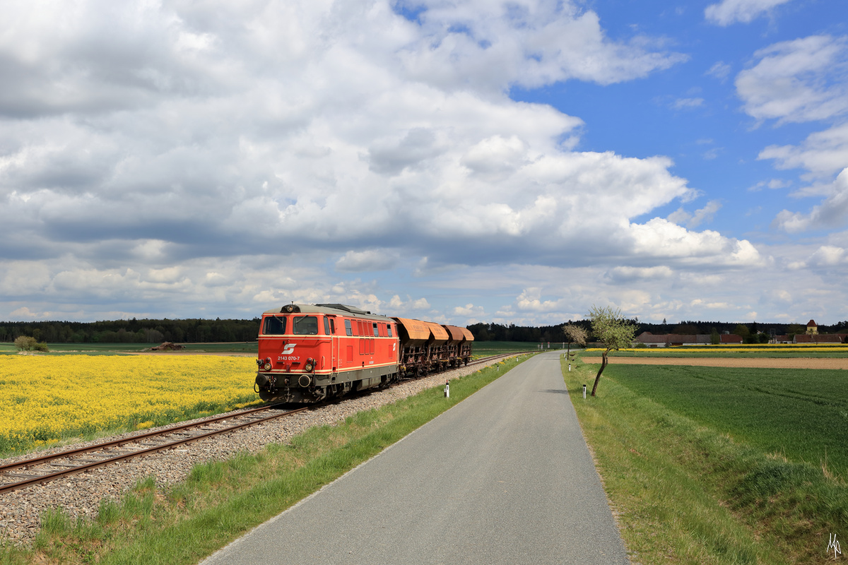 Am Sonntag, den 3. Mai 2020 war die 2143.070 insgesamt vier Mal auf der Strecke des Reblausexpress unterwegs. Aus Belastungsgründen konnte auf dieser steigungsreichen Strecke 
jeweils nur vier Wagen beladen mit Gleisschotter mitgenommen werden.
Hier hat der Zug gerade Hessendorf hinter sich gelassen.