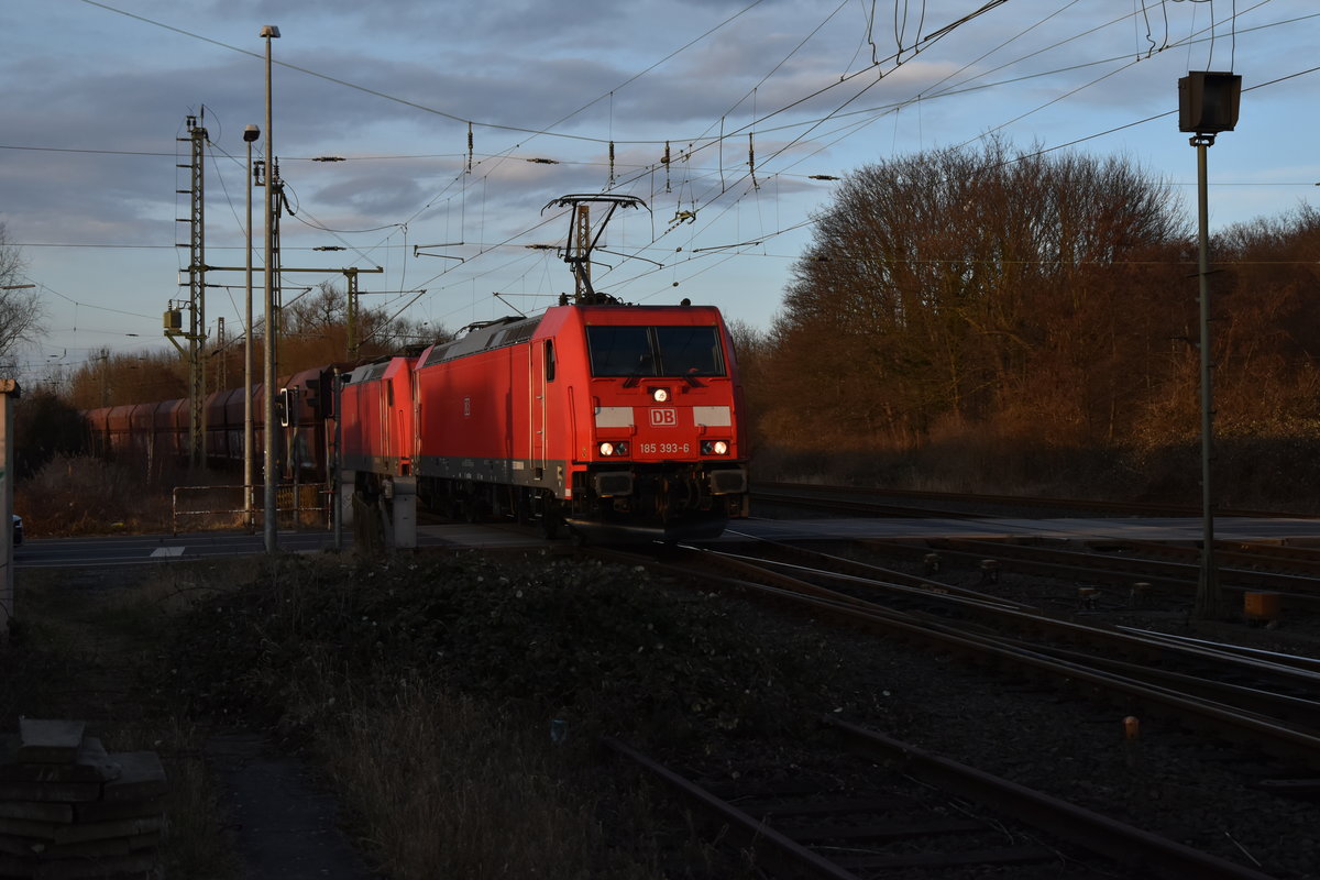 Am späteren Nachmittag des 5.3.2018 kommt die 185 393-6 mit der kalten 185 211 und einem langen Selbstentladerzug über den mittelerweile sehr schattigen Bü Blumenstraße in Grevenbroich gen Köln gefahren.