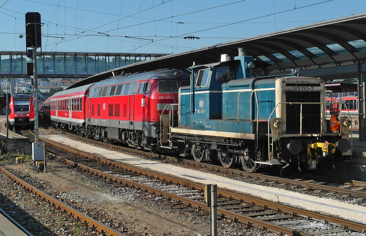 Am Spätnachmittag des 01.07.2015 hat im Ulmer Hauptbahnhof 365 143-7 die Aufgabe, 218 427-3 mit den Wagen des aus Lindau angekommenen IRE vom Gleis 3 zu ziehen, um diesen anschließend in die Abstellgruppe zu schieben.