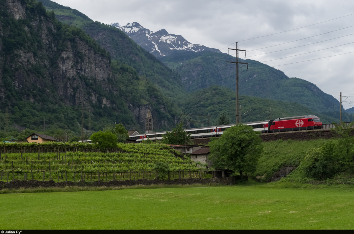Am südlichen Dorfausgang von Giornico überquert die Gotthardbahn das Tal auf einem Damm. Auf diesem befindet sich am 25. Mai 2015 die Re 460 024 mit einem InterRegio. Links einer der erstaunlich zahlreichen Weinberge Giornicos, im Hintergrund die Kirche San Michele.