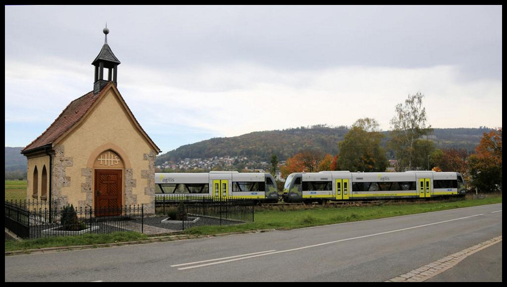 Am südlichen Stadtrand quert die KBS 821 die Pretzfelder Straße in Ebermannstadt. Unweit davon steht eine kleine schmucke Kapelle, die hier gerade am 21.10.2019 von den Agilis Triebwagen 650.736 und 650.703 passiert werden. Der Zug erreicht hier nach ca. 400 m den Bahnhof Ebermannstadt.