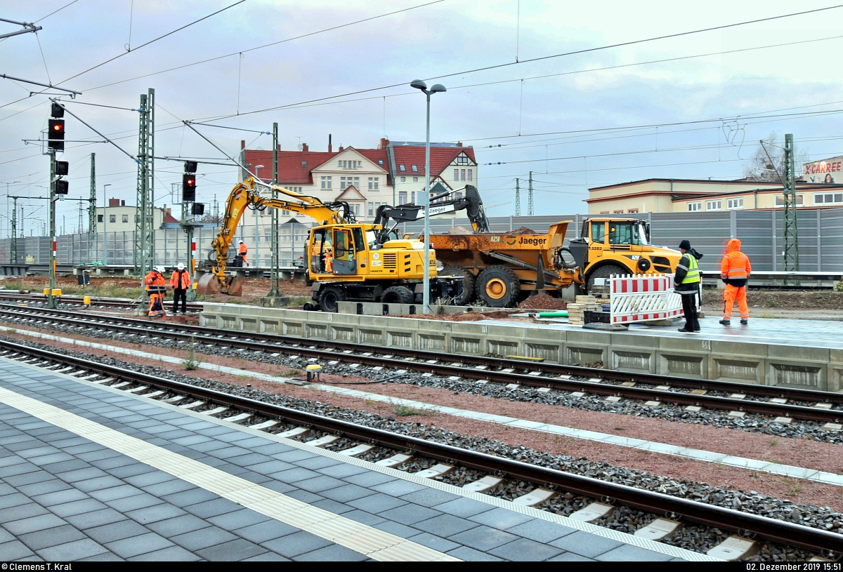 Am Tag der offiziellen Inbetriebnahme der Westseite (Gleise 4–7) in Halle(Saale)Hbf wurde mit dem Rückbau des Interimsbahnsteigs Halle(Saale)Hbf Gl. 13a auf der Ostumfahrung für den Güterverkehr (6349) begonnen. Nach vier Jahren stehen zumindest wieder 10 statt bisher 7 bzw. 8 von 13 Gleisen zur Verfügung, sodass diese im November 2016 entstandene Behelfslösung entbehrlich wird.
Hierfür rollten (Zweiwege-)Bagger und ein Kipplader von Jaeger Bernburg (Jaeger Ausbau Beteiligung GmbH + Co KG) an, um die Platten von Bahnsteig und dessen Zugang zu demontieren.
Damit fällt eine meinerseits beliebte Fotostelle nun wieder weg.

(Bild 1)
[2.12.2019 | 15:51 Uhr]
