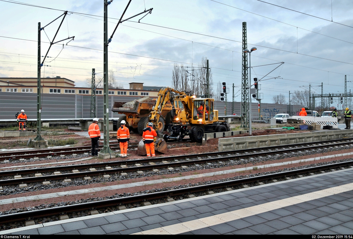 Am Tag der offiziellen Inbetriebnahme der Westseite (Gleise 4–7) in Halle(Saale)Hbf wurde mit dem Rückbau des Interimsbahnsteigs Halle(Saale)Hbf Gl. 13a auf der Ostumfahrung für den Güterverkehr (6349) begonnen. Nach vier Jahren stehen zumindest wieder 10 statt bisher 7 bzw. 8 von 13 Gleisen zur Verfügung, sodass diese im November 2016 entstandene Behelfslösung entbehrlich wird.
Hierfür rollten (Zweiwege-)Bagger und ein Kipplader von Jaeger Bernburg (Jaeger Ausbau Beteiligung GmbH + Co KG) an, um die Platten von Bahnsteig und dessen Zugang zu demontieren.
Damit fällt eine meinerseits beliebte Fotostelle nun wieder weg.

(Bild 4)
[2.12.2019 | 15:54 Uhr]