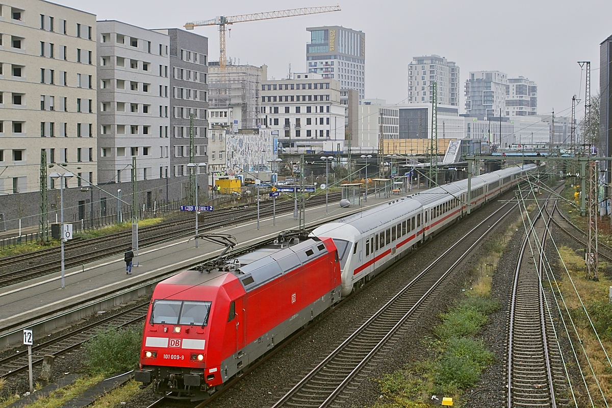 Am trüben 15.12.2023 durchfährt 101 009-9 mit einem IC den S-Bahn-Haltepunkt Düsseldorf-Wehrhahn. Im Hintergrund das  Quartier Central , das in den vergangenen Jahren auf dem Gelände des früheren Güterbahnhofes Derendorf entstand.