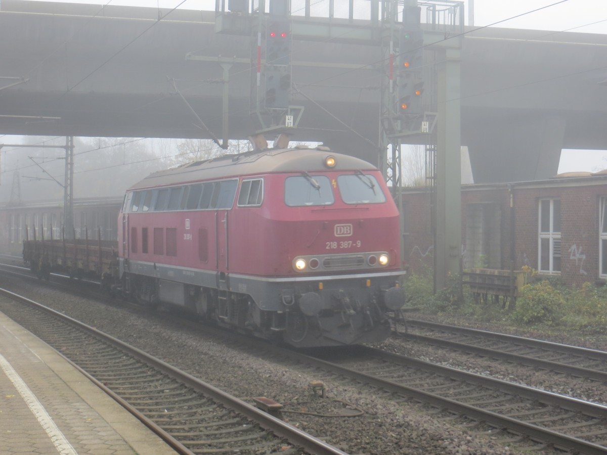 Am vernebelten 21.11.2014 durchfuhr die 218 387-9 mit einem Flachwagen den Bahnhof Hamburg-Harburg. 