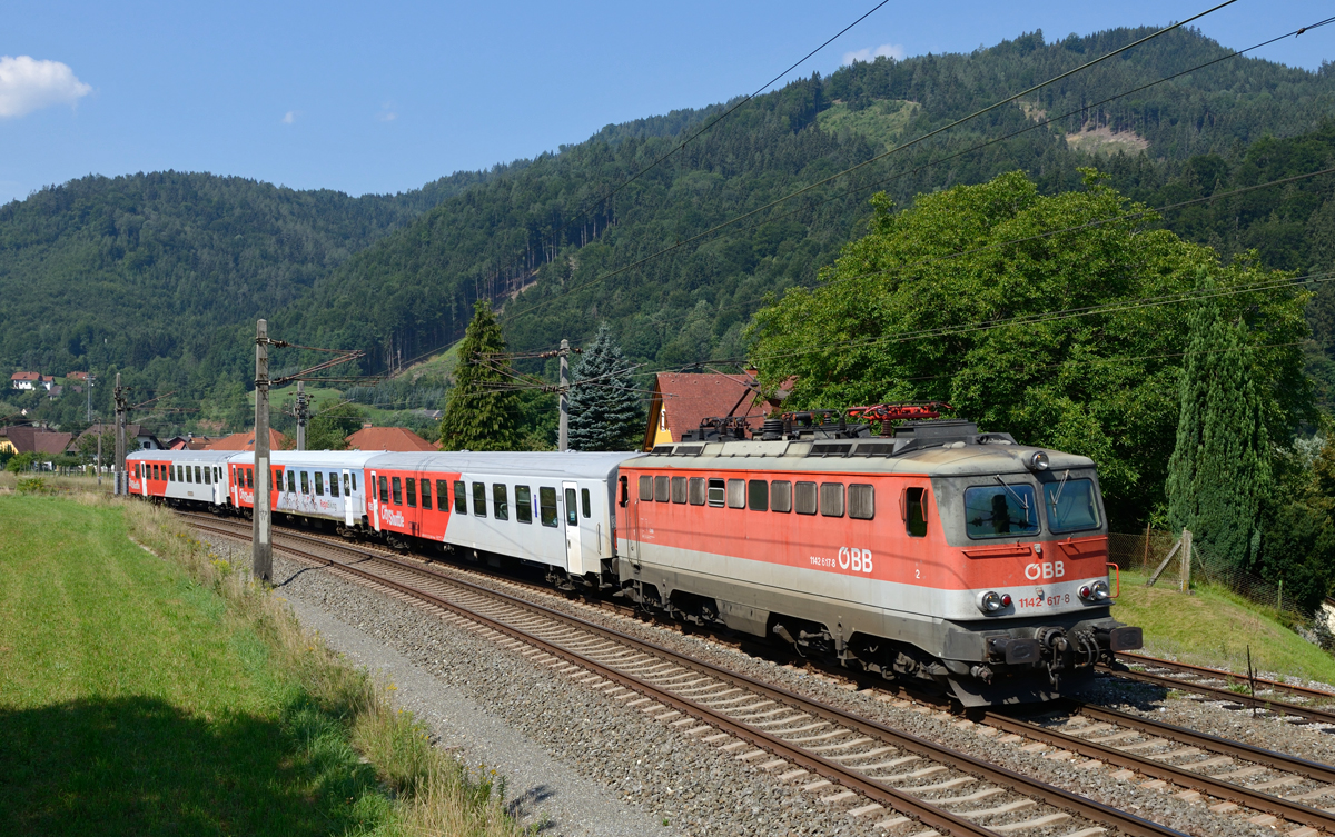 Am Vormittag des 10. August 2015 war die 1142 617 mit einem Schnellbahnzug von Graz Hauptbahnhof nach Bruck an der Mur unterwegs, und wurde von mir in Peugen bei Frohnleiten fotografiert.