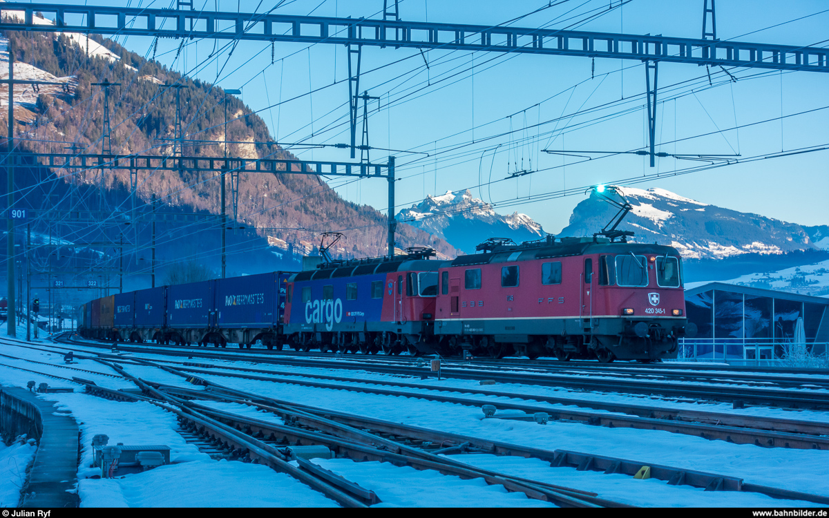 Am Vormittag des 24. Dezembers 2017 fahren die Re 4/4 II 11345 und die Re 6/6 11678  Bassersdorf  mit einem UKV-Zug unter lautem Knistern der rauhreifbesetzten Fahrleitung in den Bahnhof Frutigen ein.