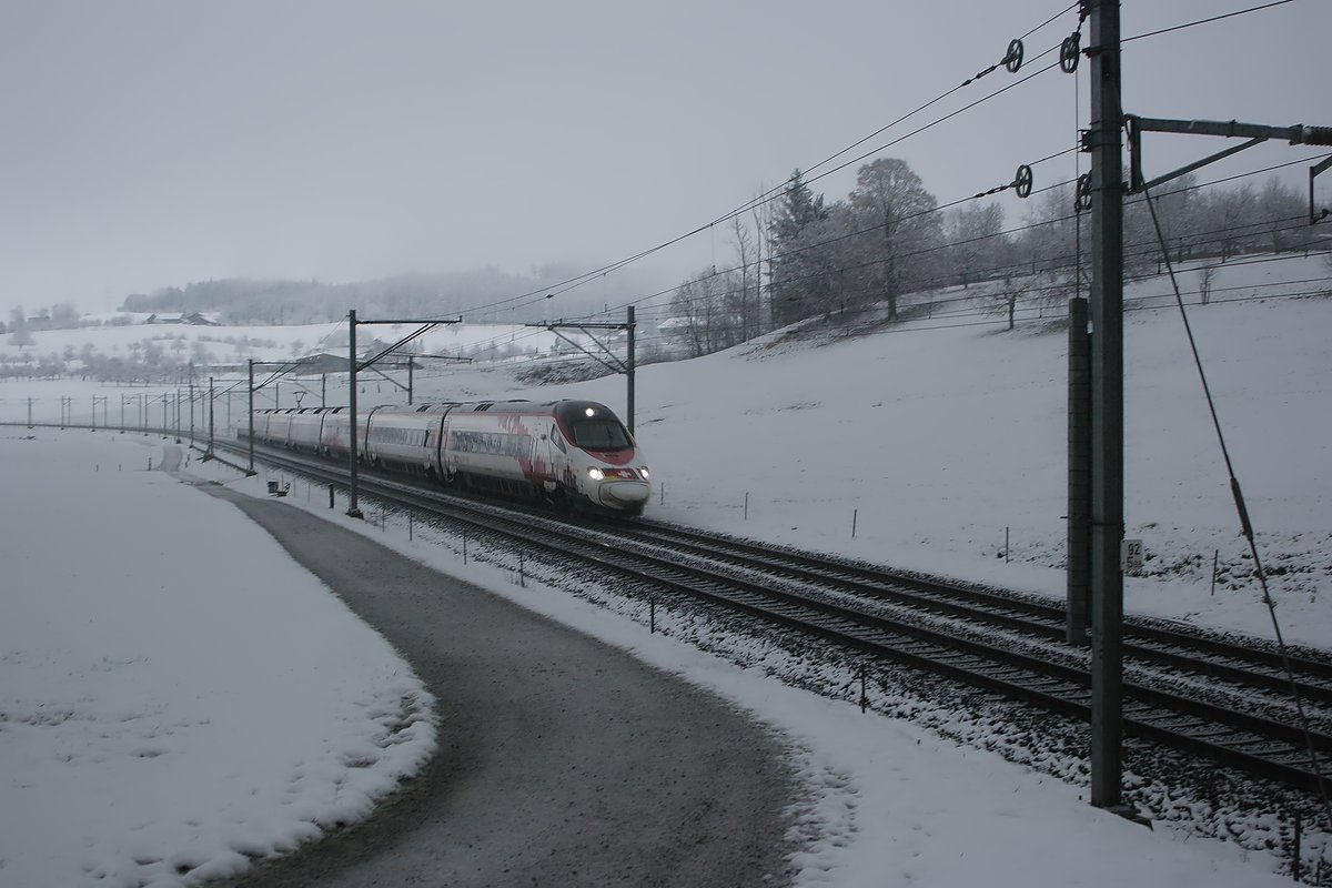 Am Weihnachtstag fand ich Zeit, einen Spaziergang zu machen. Dafür begab ich mich auf die Strecke zwischen Flawil und Gossau.
War das Licht bisher schon trüb, so kam jetzt gerade noch genug Helligkeit für den erwarteten Eurocity aus München, bevor es dann ganz zu tat. So schaffte ich es gerade noch, bei leichtem Schneefall den RABe 503 022  Johann Wolfgang von Goethe  auf dem Weg nach Zürich abzulichten.

Gossau Espel, 25.12.2020
