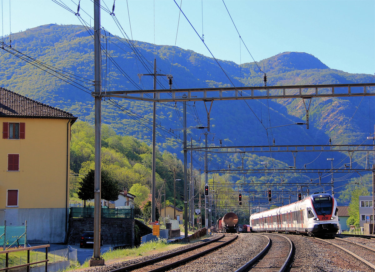 An der alten Ceneri-Strecke Bellinzona-Lugano (wird bald durch einen Basistunnel ersetzt): Nach Durchfahrt durch den Ceneri-Tunnel erreicht die Linie ihre Passhöhe in Rivera Bironico. TILO Flirt 524 108 fährt im Morgenlicht von Lugano her in Rivera Bironico ein, während ein langer Güterzug in die Gegenrichtung nach Süden fährt. 6.Mai 2019  