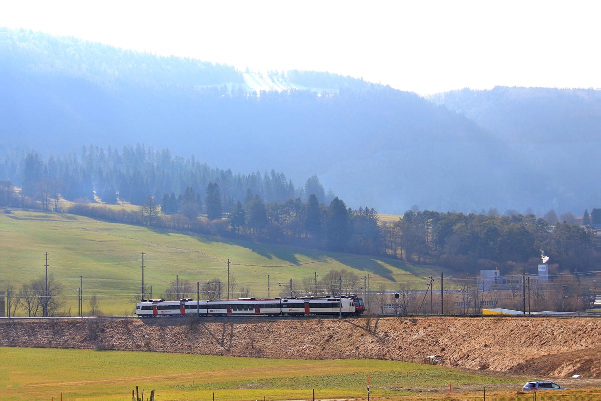 An einem diesigen Tag im Berner Jura fährt ein SBB Domino-Lokalzug in die grosse Schlaufe oberhalb Sonceboz ein zur Fahrt durch das Gebirge Richtung Tavannes. Im Hintergrund die Linie geradeaus talaufwärts nach La Chaux-de-Fonds. 19.Februar 2018 