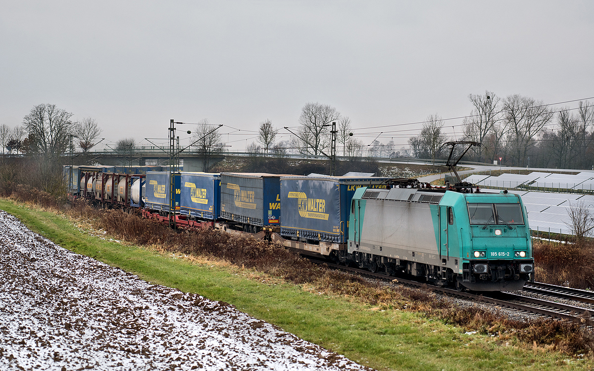 An einem grauen Tag fährt die 185 615-2 in Langenisarhofen mit einem LKW Walter Sattelaufliegerzug vorüber.Bild 5.12.2017