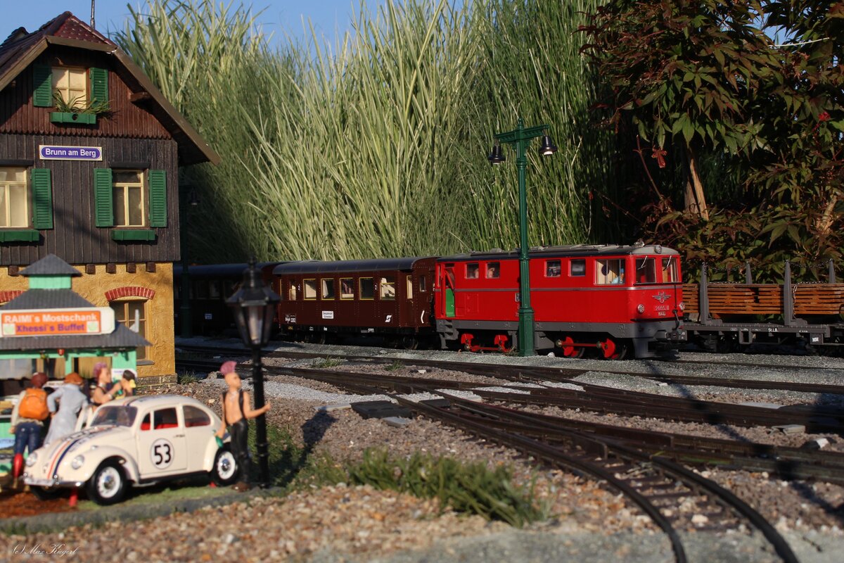 An einem lauen Sonntag Abend steht die 2095.11 mit einem kurzen Regionalzug, der der letzte nach Garting ist, in Brunn am Berg und wartet auf die Abfahrt.
Ob den  Punks  die sich am Bahnhofsvorplatz versammelt haben der Sound der 2095 oder des 1963 gebauten VW Käfers besser gefällt istvnicht bekannt.
Bild vom 15.8.2023