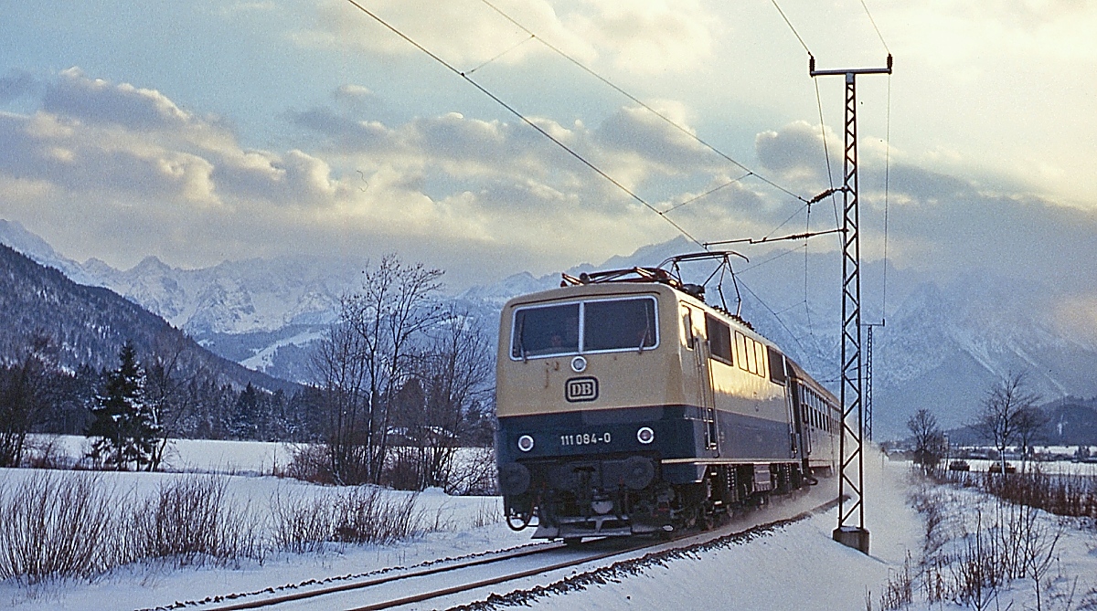 An einem Nachmittag Anfang Januar 1980 ist 111 084-0 mit einem Eilzug nach München zwischen Farchant und Oberau unterwegs
