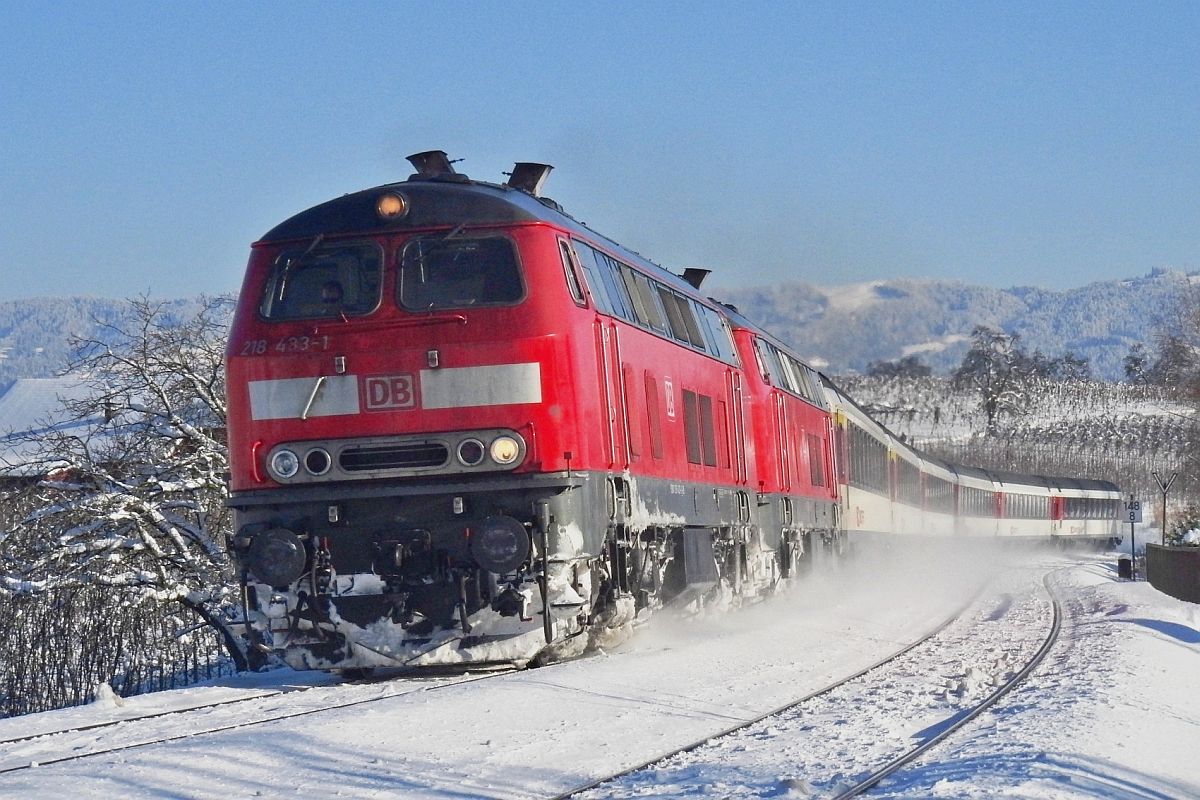 An einem schnen Wintertag ziehen 218 433-1 und eine weitere 218er kurz nach der Abfahrt in Lindau die Wagen des EC 195 auf der Fahrt von Zrich nach Mnchen die Steigung hinauf ins Allgu (Bodolz, 10.02.2013).