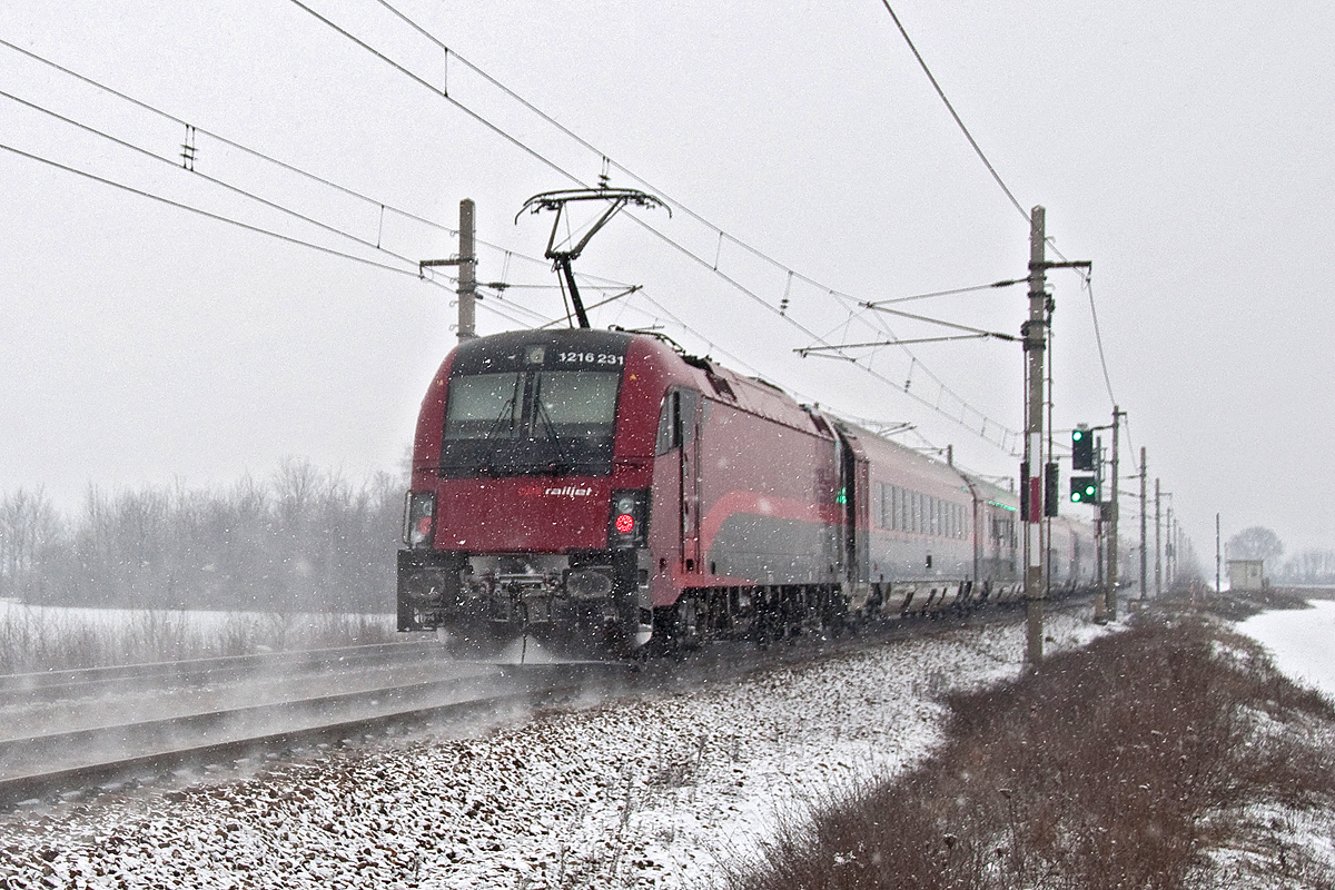 An einem der wenigen Tage im Winter 2016, als es im Osten Österreichs etwas Schneefall gab, am 23.01.2016, entstand diese Aufnahme: 1216 231, unterwegs mit dem railjet 76 von Graz nach Prag, kurz nach Wien Süßenbrunn.