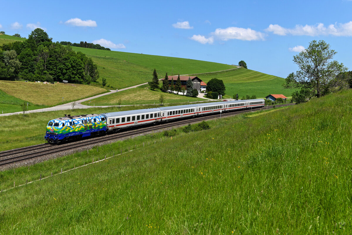 An der Günzachquelle warteten am 04. Juni 2022 diverse Fotografen auf den IC 2085 nach Oberstdorf. Grund war der Einsatz der 218 443 von DB Gebrauchtzug vor dieser Leistung. Die Lok war zum Aufnahmezeitpunkt erst wenige Tage mit ihrer neuen Lackierung im Einsatz, die an den ehemaligen Touristikzug der Deutschen Bahn erinnert. In der Ausführung gibt es jedoch einige Unterschiede, im Vergleich zu den einst in der Farbgebung gehaltenen 218 416 und 418 wurde bei der 218 443 mehr Weiß bei den stilisierten Wolken verwendet und das Dach wurde nicht komplett lackiert. Ungeachtet dessen freut man sich natürlich über das neue Schmuckstück, deren Vorgängerinnen auch oft im Allgäu zum Einsatz kamen. 