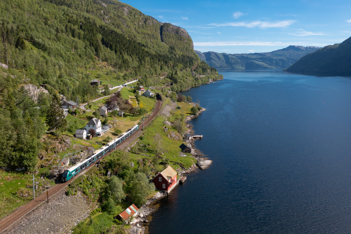 An der Küste des Veafjordes liegen unzählige kleine Hütten und Bootshäuser. An diesen schlängelt sich die Bergenbahn bis Stanghelle entlang. Kurz vor Stanghelle ist Zug 1826 von Bergen nach Myrdal unterwegs.