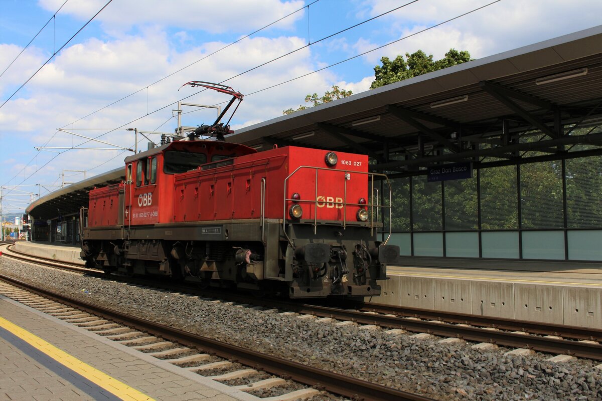 An Mittwoch und Freitagen wird der VG73709 von Messendorf nach Graz Vbf regelmäßig zu schwer für die planmäßige 2068 und deshalb wird in solchen Fällen ab Graz Ostbahnhof ein Vorspanntriebfahrzeug benötigt, das als Lokzug zugeführt wird.
Sekunden bevor die berüchtigte  Fotowolke  aufzog entstand am 8.9.2021 das Bild der 1063 027, die als GLZ87448 von Graz Hbf nach Graz Ostbahnhof unterwegs war und sich in der Haltestelle Graz Don Bosco in den überhöhten Bogen legt.
Die Haltestelle Graz Don Bosco gehört betrieblich gesehen noch zum Bahnhof Graz Hbf und die eigentlichen Ausfahrsignale befinden sich kurz hinter der den Bahnsteigen.