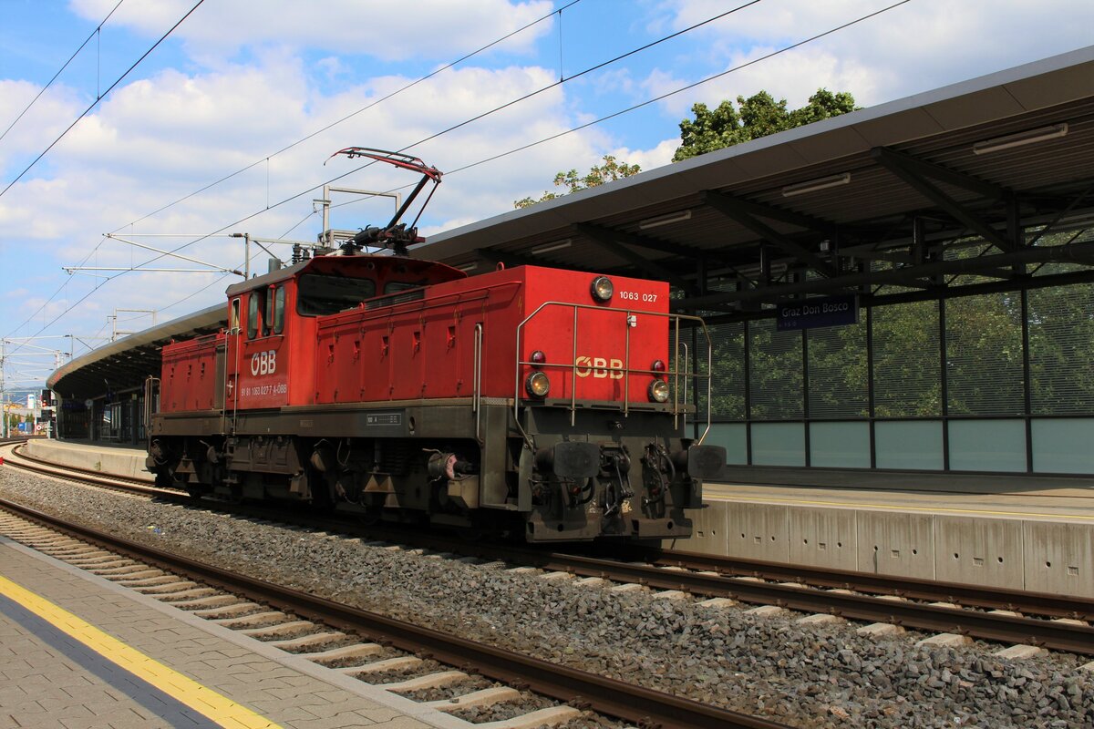 An Mittwoch und Freitagen wird der VG73709 von Messendorf nach Graz Vbf regelmäßig zu schwer für die planmäßige 2068 und deshalb wird in solchen Fällen ab Graz Ostbahnhof ein Vorspanntriebfahrzeug benötigt, das als Lokzug zugeführt wird.
Sekunden bevor die berüchtigte  Fotowolke  aufzog entstand am 8.9.2021 das Bild der 1063 027, die als GLZ87448 von Graz Hbf nach Graz Ostbahnhof unterwegs war und sich in der Haltestelle Graz Don Bosco in den überhöhten Bogen legt.
Die Haltestelle Graz Don Bosco gehört betrieblich gesehen noch zum Bahnhof Graz Hbf und die eigentlichen Ausfahrsignale befinden sich kurz hinter der den Bahnsteigen.