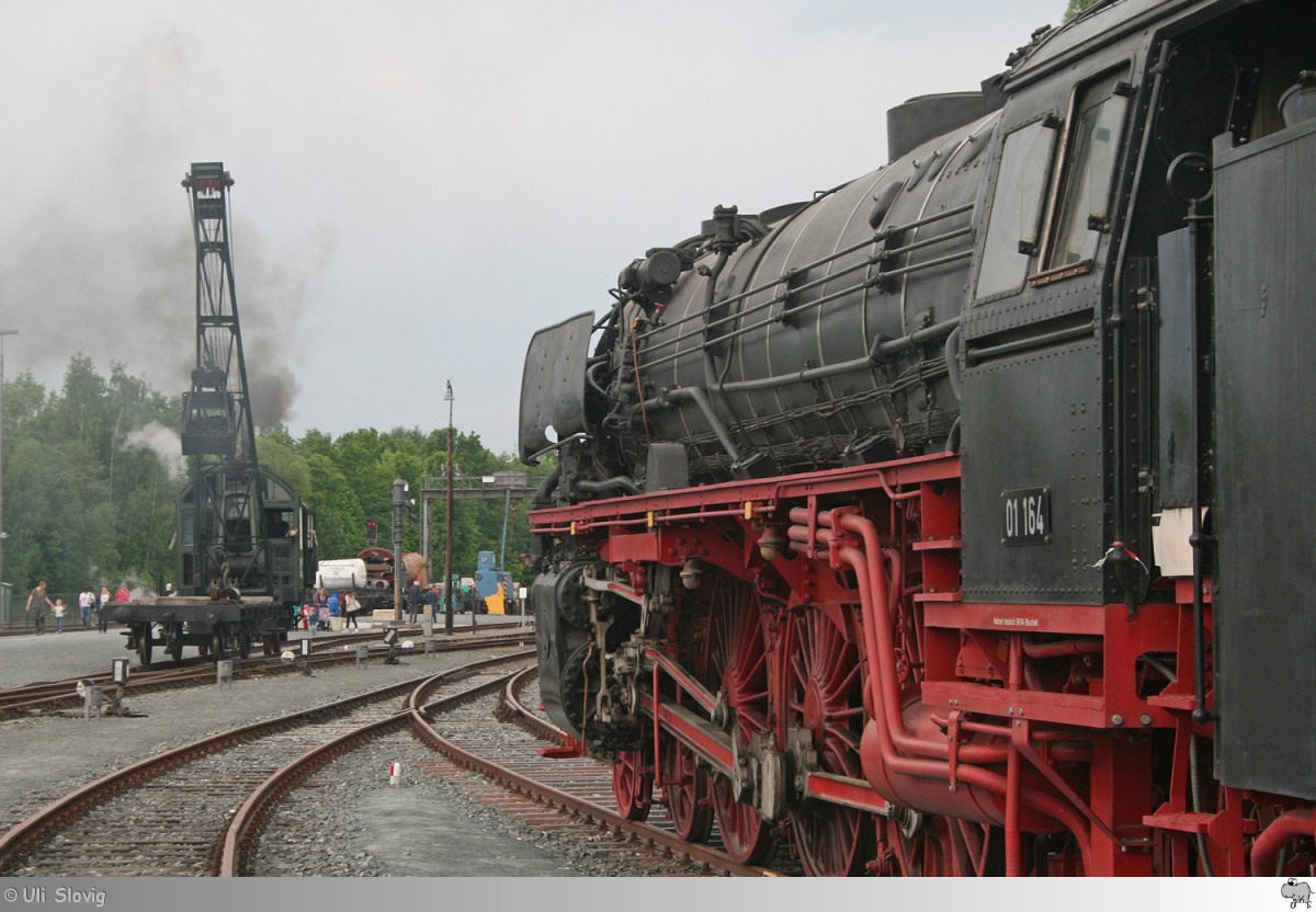 An den Pfingstdampftagen 2015 im Deutschen Dampflokomotiv Museum in Neuenmarkt-Wirsberg rollt der alte Demag Dampfkran an der 01 164 vorbei. Die Aufnahme entstand am 25. Mai 2015.