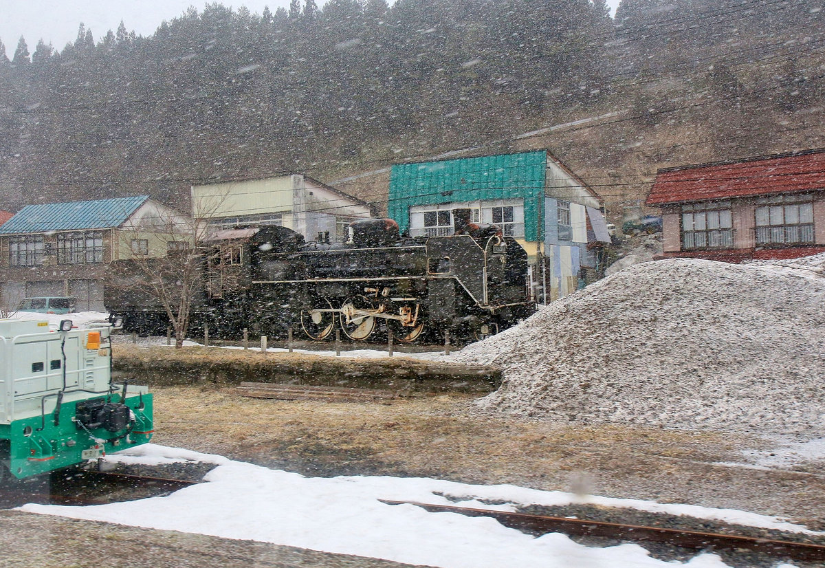 An der Querverbindung vom Pazifik zum Japanischen Meer via der Yamagata Hochebene. In einem Blizzard schlummert die C58 356 als Erinnerung an ihre schweren Dienste auf dieser Strecke still vor sich hin, bildlich eingeklemmt zwischen einem Bahndienstwagen und einem Schneehaufen. Nakayama-daira Onsen, 17.März 2019 