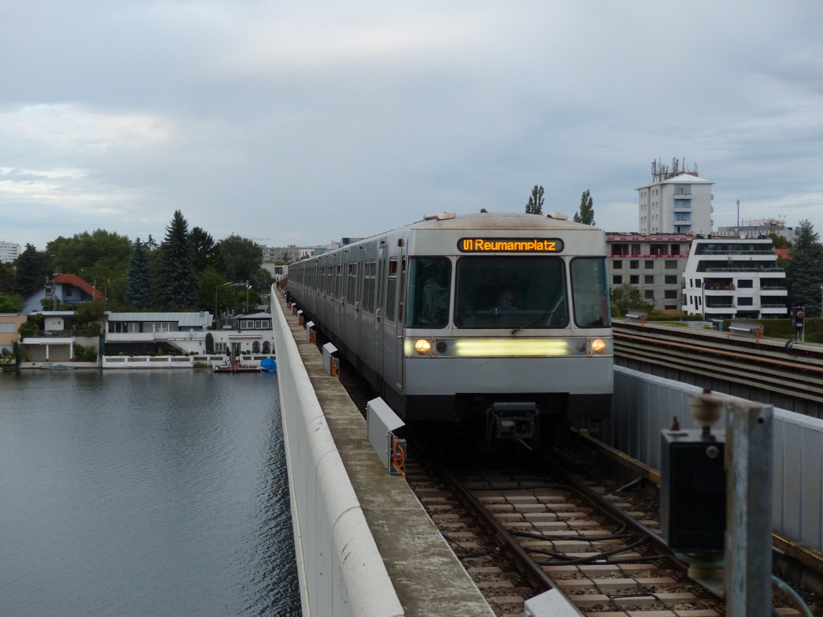 An der Station Alte Donau fährt ein U-Bahn-Zug der Linie U1 zum Reumannplatz ein. Die Alte Donau, ein Seitenarm der Donau, ist im Bild zu sehen. 25.8.2015