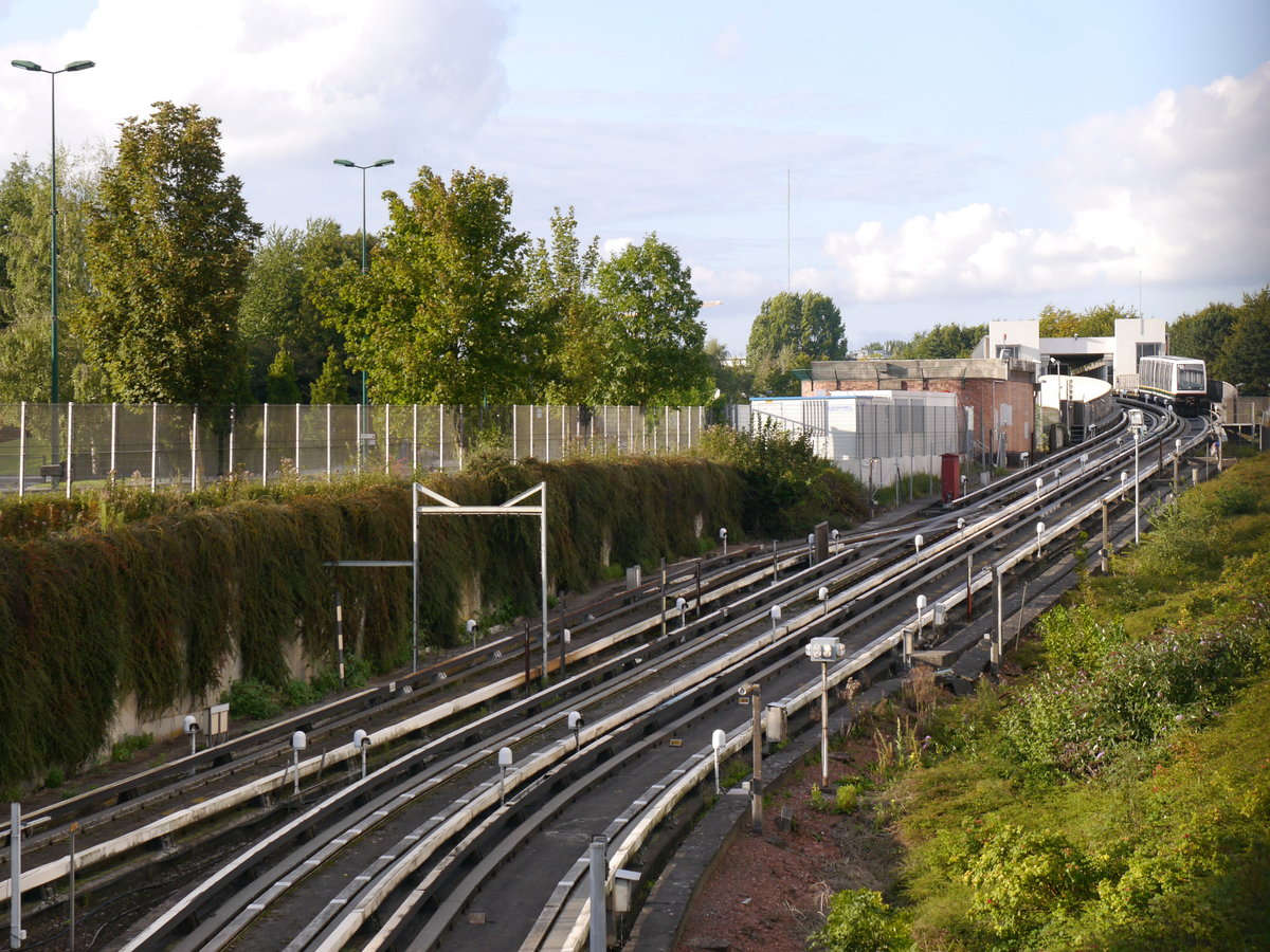 An der Station Quatre-Cantons-Stade startet Fahrzeug 103 (Typ VAL208 Siemens) der Métro Lille die Fahrt auf der Ligne 1.
Hier in Villeneuve d'Ascq bei Lille nimmt die VAL-Strecke ihren Anfang und hier liegen auch die Anfänge des VAL-Systems. Die Konzept einer leichten automatischen Métro wurde an der Universität Lille ab 1968 entwickelt. Die erste konzipierte Strecke war: Villeneuve d'Ascq à Lille, abgekürzt VAL. Nachdem das System dann erfolreich war, wurde VAL dann zum benannten Akronym für: Véhicule Automatique Léger (leichtes automatisches Fahrzeug). Ab 1977 begann der Bau und 1983 wurde die Linie 1 der Métro Lille eröffnet. 
2014-08-31 Villeneuve d'Ascq Quatre-Cantons-Stade