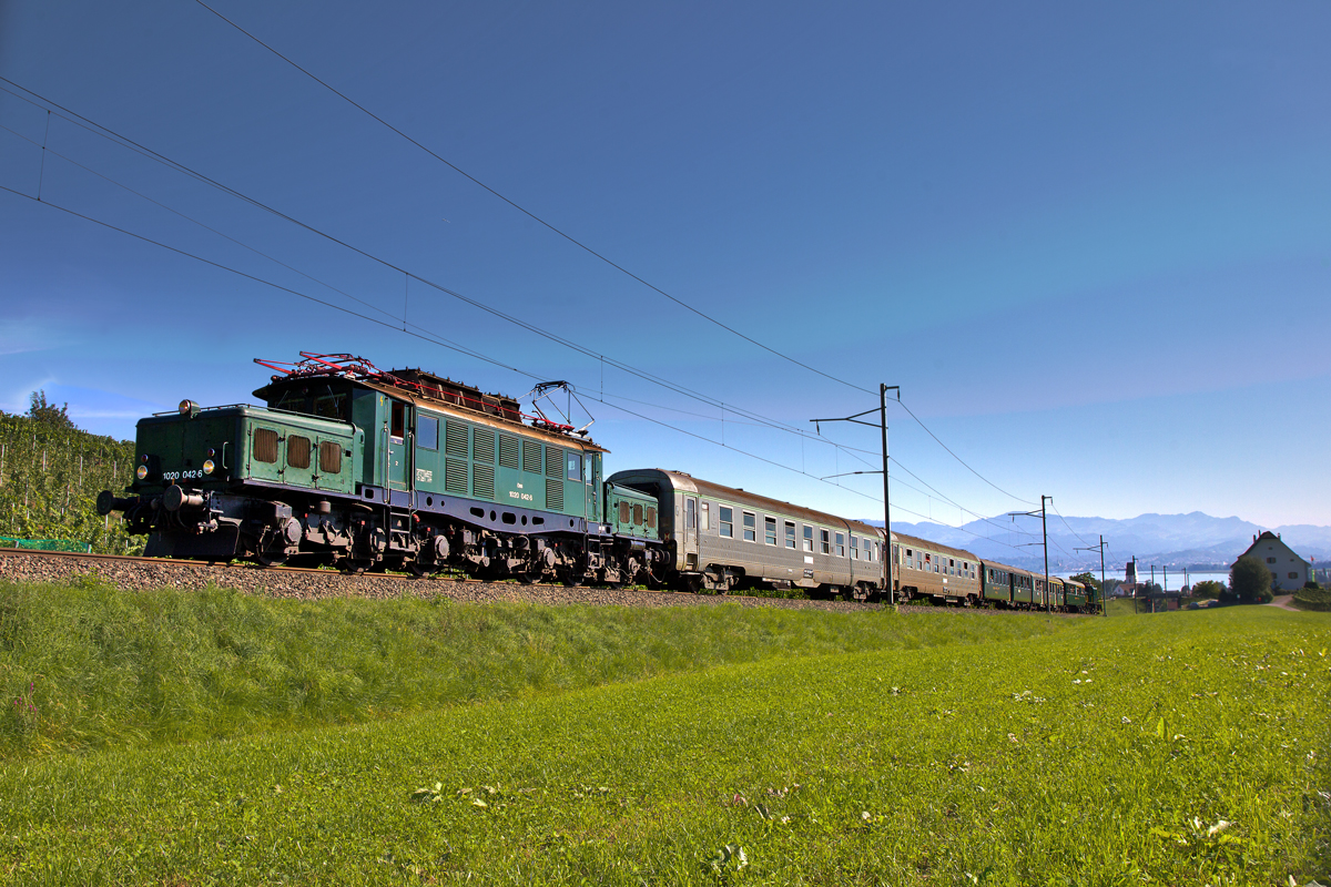 An der Steilrampe in den Leutschner Weinbergen von Freienbach fährt die OeBB E-Lok 1020 042-6 mit einem Sonderzug aus Pfäffikon SZ nach Luzern zusammen mit der Schublok Be 6/8 III 13302 die Steigung hinauf.Bild vom 29.8.2015