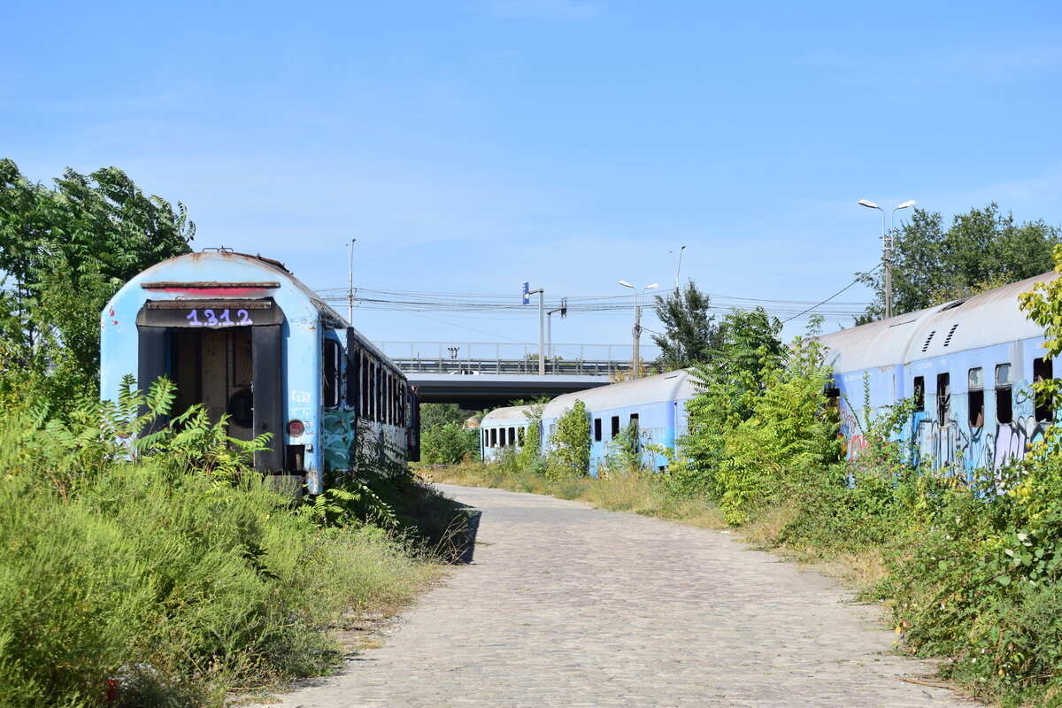 An der Zufahrt zur westlichen Abstellung vom Depot Bukarest stehen zahlreiche z-gestellte Reisezugwagen abgestellt. Die Wagen sind vom Vandalismus und Rost schwer gezeichnet.

Bukarest 04.09.2025
