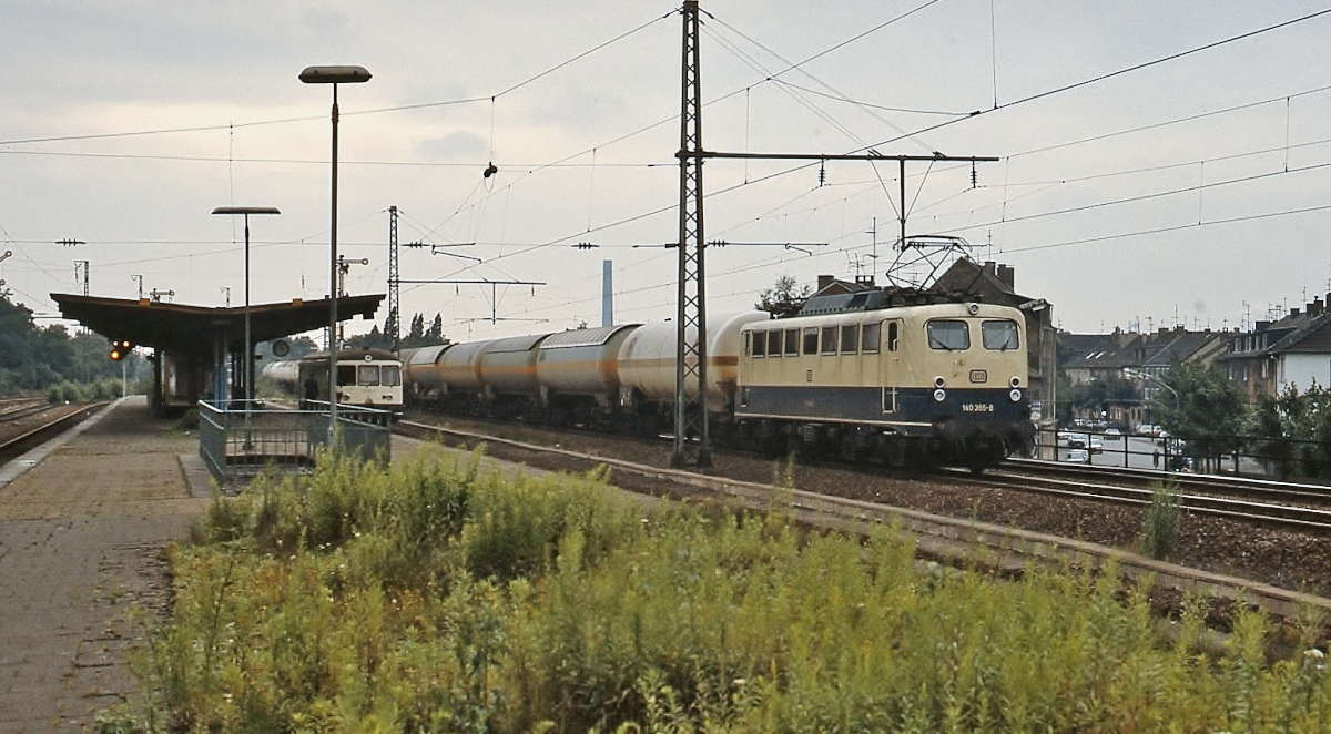 Anfang der 1990er Jahre durchfährt 140 365-8 den Bahnhof Duisburg-Meiderich, am Bahnsteig steht ein Akkutriebwagen der Baureihe 515