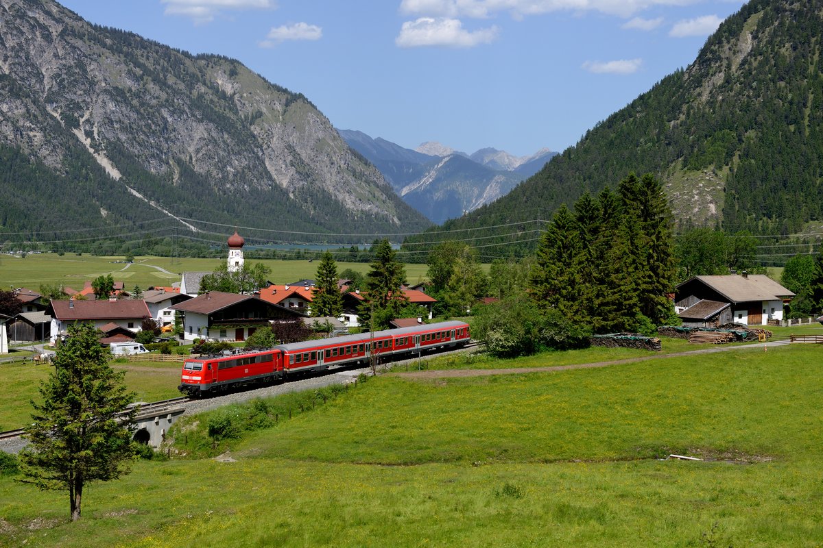 Anfang Juni 2014 gab es wieder einmal die Gelegenheit, lokbespannte Personenzüge im Außerfern zu fotografieren. Als 425-er Ersatz kamen zeitweise sogar zwei 111-er mit n-Wagen zum Einsatz. Am 08. Juni konnte 111 031 mit der RB 5521 nach Garmisch-Partenkirchen bei Heiterwang abgelichtet werden. Im Hintergrund kann man sogar den Plansee erkennen.