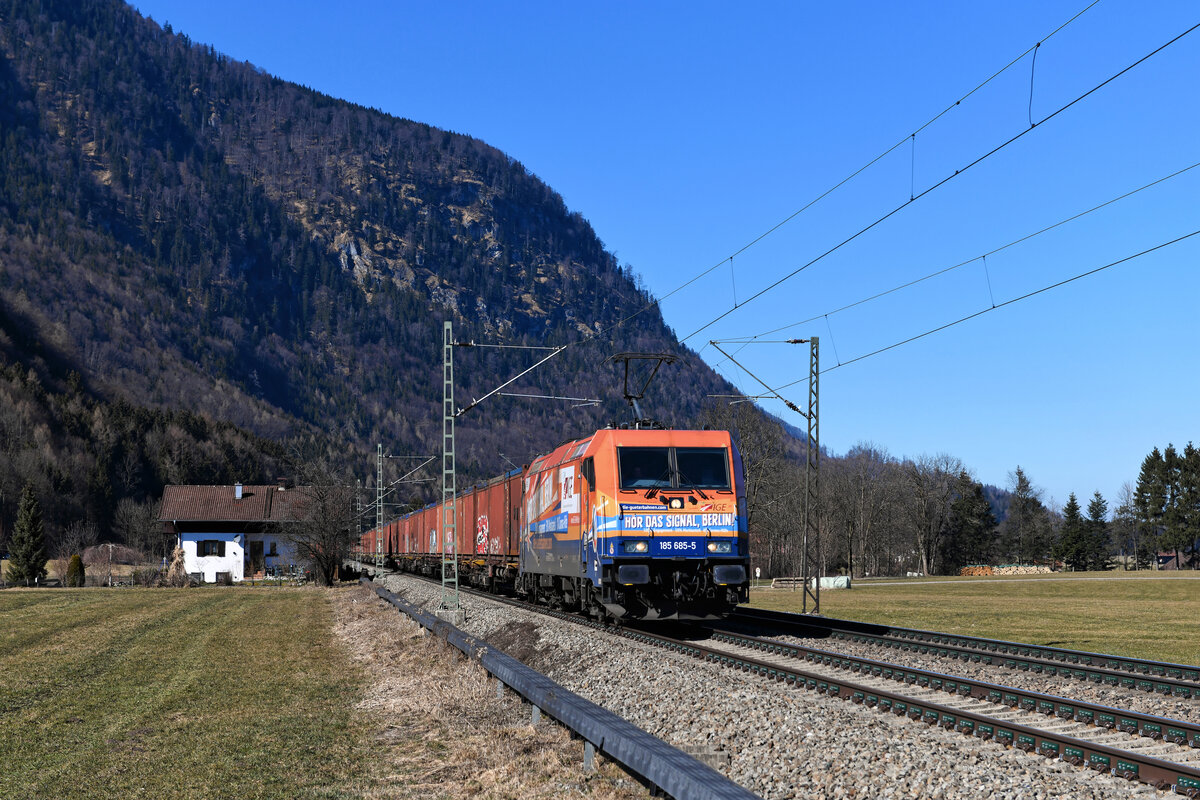 Anfang März diesen Jahres fuhr die 185 685 der IGE für einige Tage für TXLogistik. Die Lok weist eine auffällige Gestaltung auf und trägt den Schriftzug  Hör das Signal, Berlin! . Im September 2020 fand eine Demonstration auf Schienen statt, mit der drei Botschaften ins Regierungsviertel der Hauptstadt getragen wurden. Erstens: Es gibt viele Güterbahnen und diese sind leistungsbereit. Zweitens: Bei der geplanten Hilfe in der Corona-Krise dürfen die Wettbewerber vom Bund nicht schlechter behandelt werden als die Deutsche Bahn. Drittens: die Entlastung der Straßen vom Güterverkehr mit Hilfe der Schiene braucht mehr politischen Druck. 20 Loks von verschiedenen privaten EVUs, die in Summe mehr als 100.000 Kilowatt Leistung auf die Schiene brachten, verschafften sich auf der Berliner Stadtbahn bei der Fahrt durch das Regierungsviertel lautstark Gehör. Aktuell trägt die Traxx-Maschine nach wie vor ihre Folierung. Am 02. März 2021 konnte ich sie bei Niederaudorf im Inntal vor dem DGS 43883 von Bad Bentheim nach Lugo fotografieren. Mit den geladenen Containern wird üblicherweise Müll von Italien nach Deutschland transportiert.  